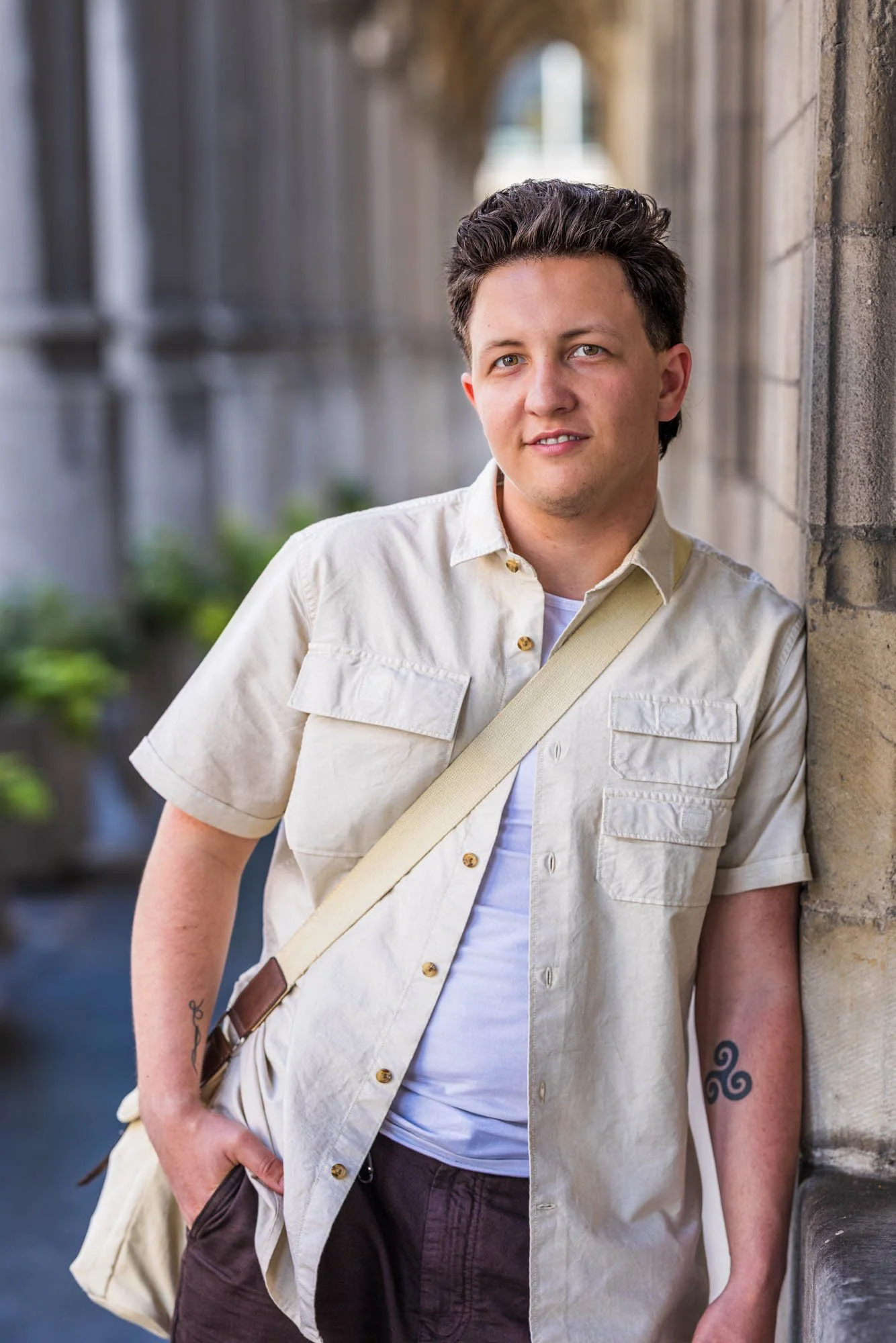 "Halftotaal portret van Alex Verspecht in lichtbeige hemd met korte mouwen, poserend langs een historische gevel in Mechelen"
