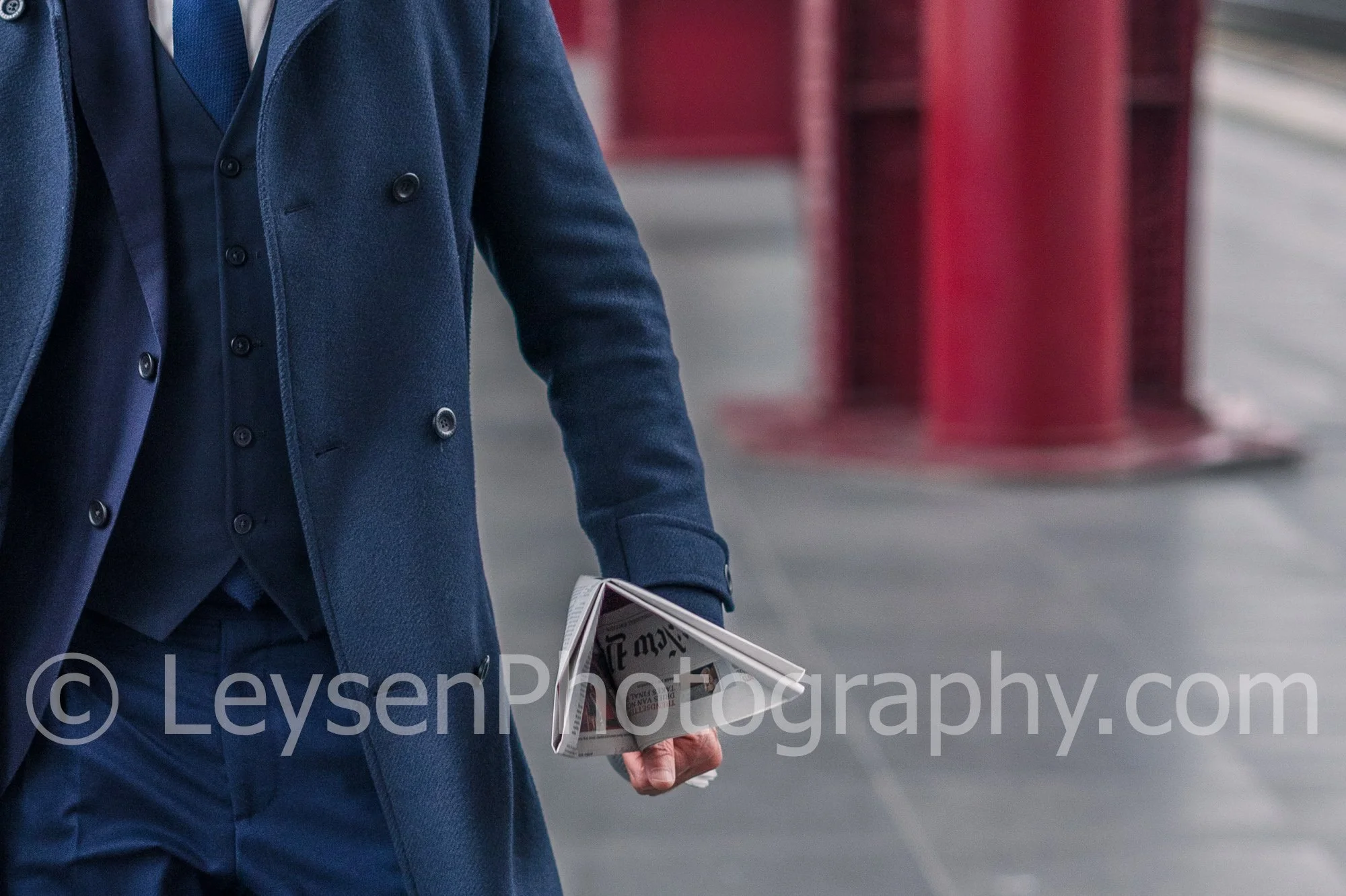 Professional businessman walking along urban train station with news paper - Close-up
