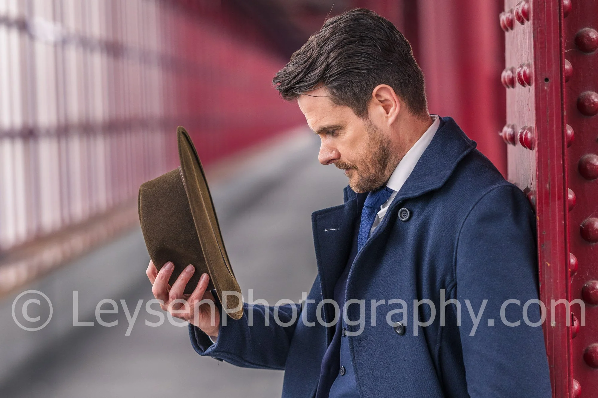 Business Executive Holding Hat in Urban Architectural Setting