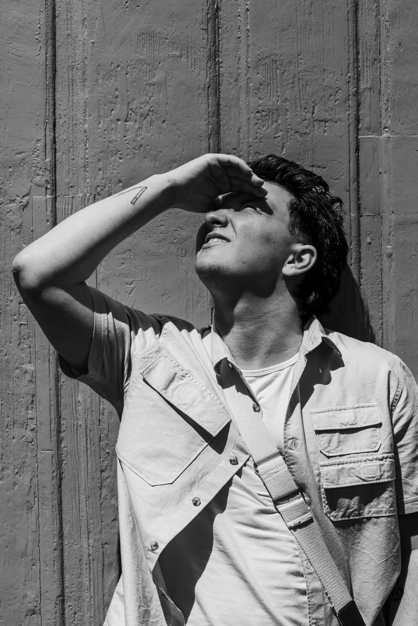 zwart wit portret van Alex verspecht, met zonlicht in zijn gezicht. harde schaduwen tegen de deur. locatie Mechelen, achter de sint Romboutstoren 