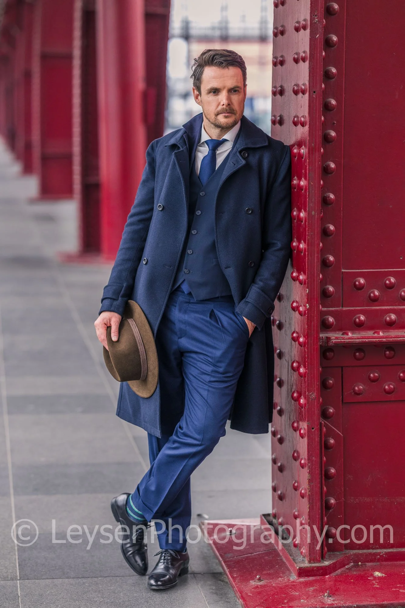 Confident Business Executive Leaning Against Red Steel Architecture