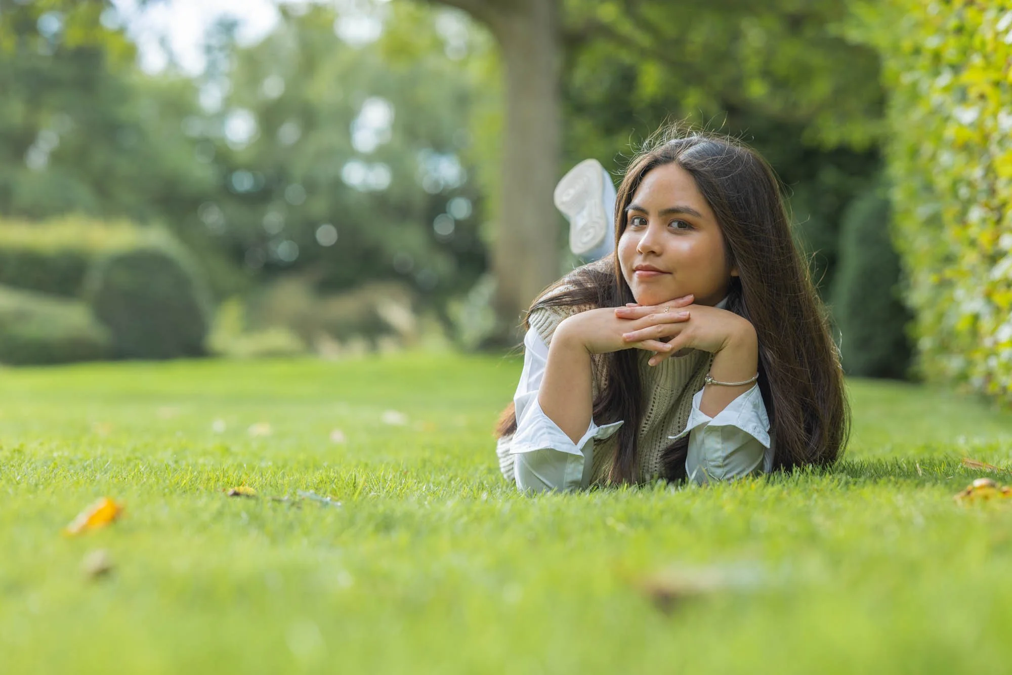 Portretfotograaf Mechelen – ontspannen lifestyle portret in park, aziatische vrouw liggend in gras met speelse uitstraling
