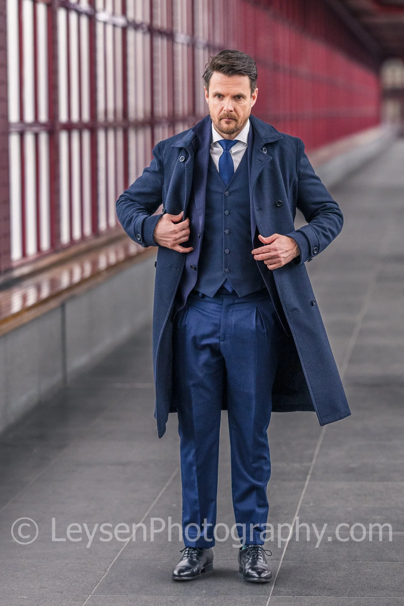 Confident executive adjusting coat while walking in urban corridor