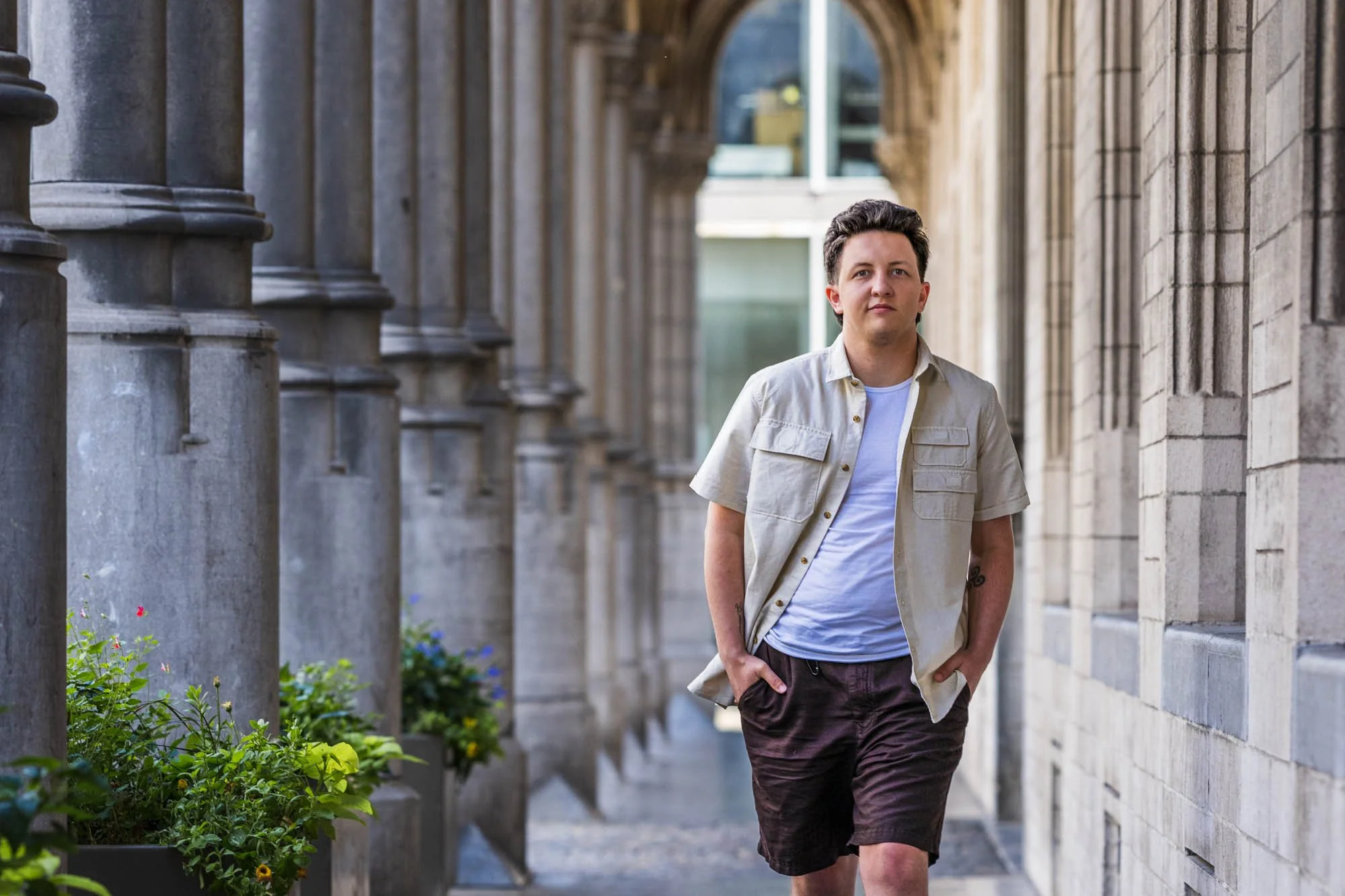 Volledige portretopname van Alex Verspecht al wandelend langs een colonnade in Mechelen, tijdens een branding fotosessie"
locatie; zijkant van het historische stadhuis.