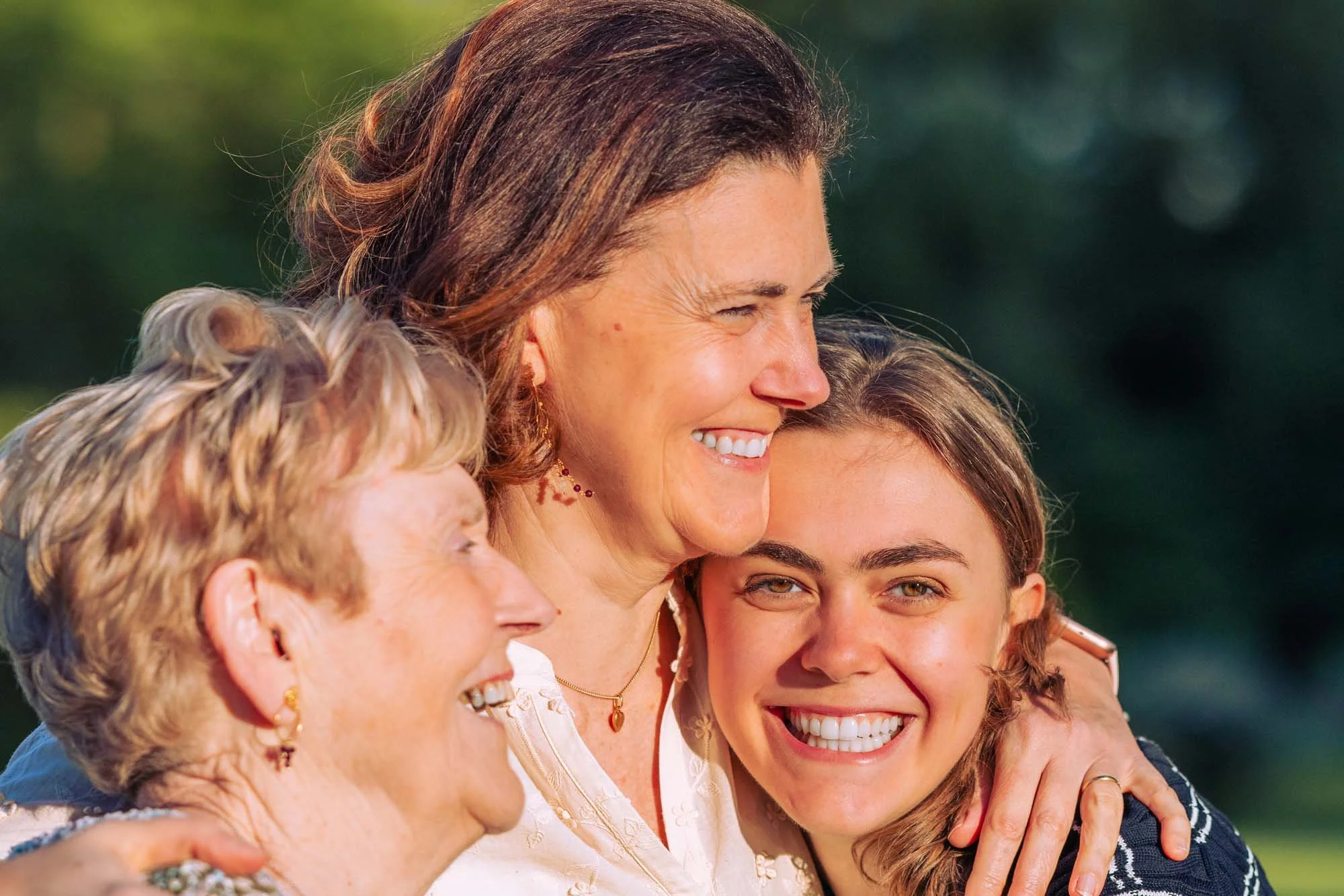 "Drie generaties vrouwen – grootmoeder, mama en Amber Sels – samen in een warme omhelzing, gefotografeerd bij zonsondergang in Rijmenam"