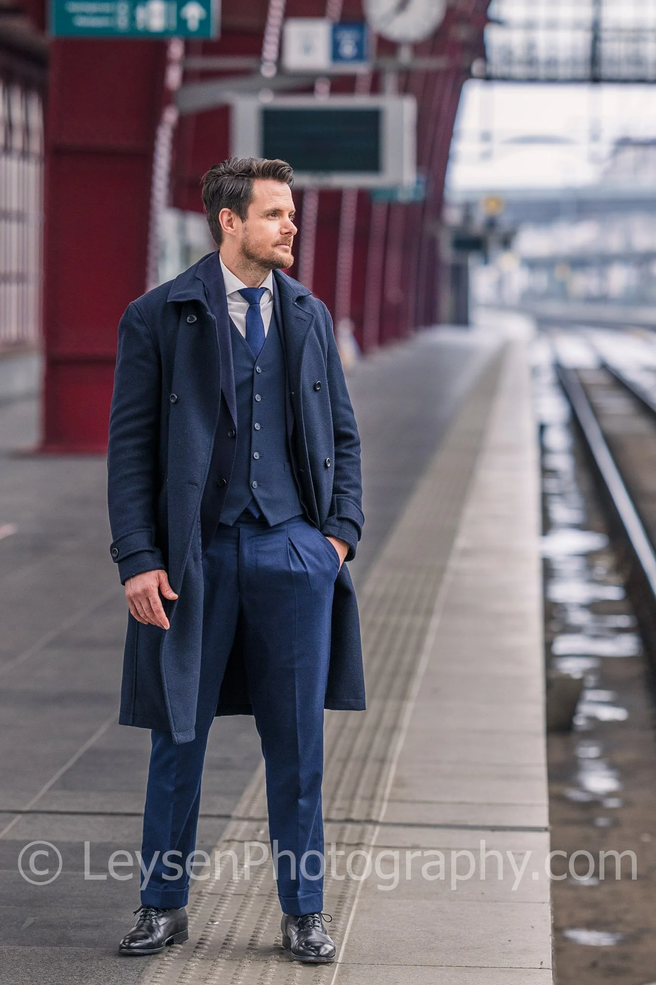 Elegant Businessman Standing on Train Platform in Business Suit