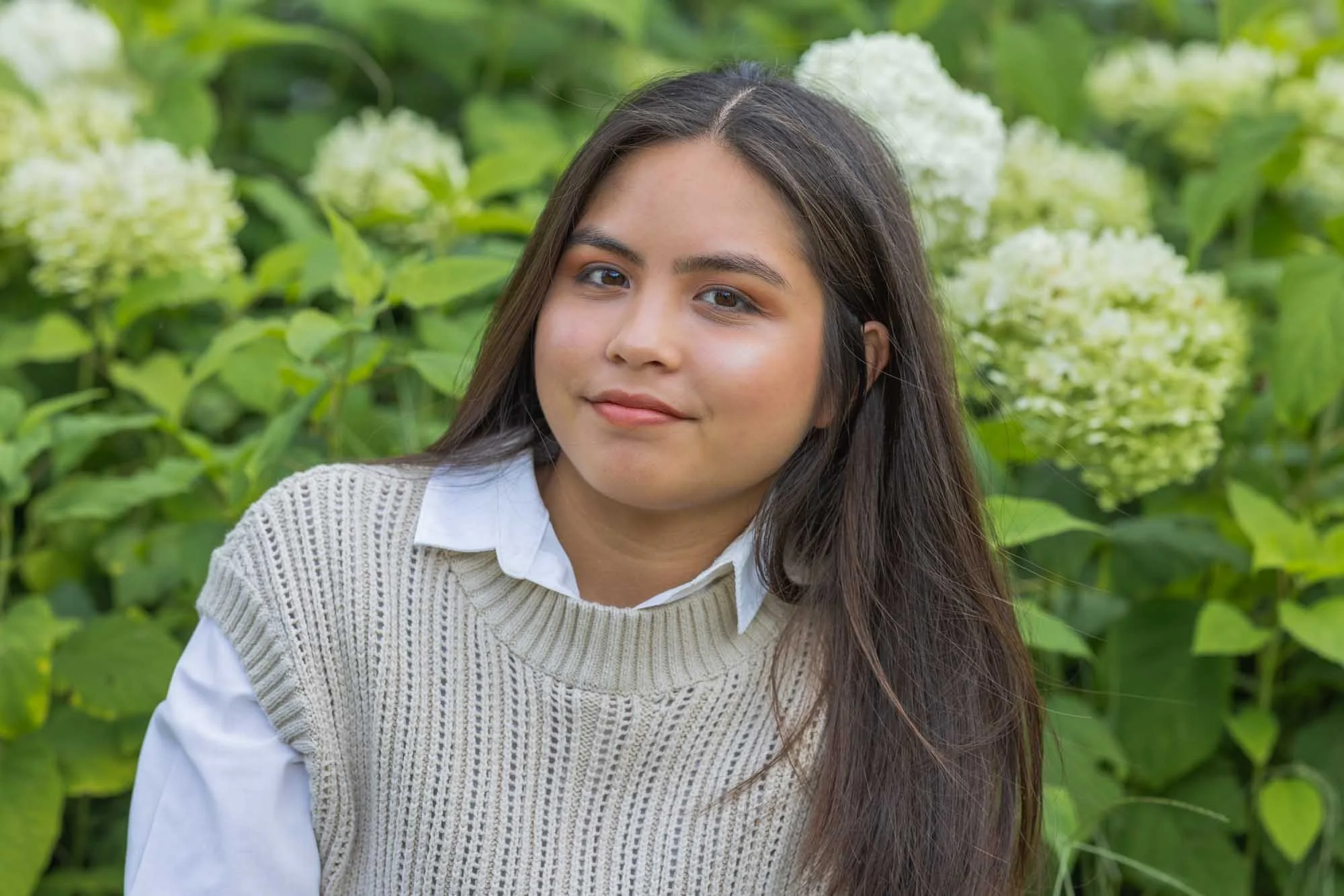 Portretfotografie Mechelen – frisse uitstraling voor witte hortensia’s, vrouw kijkt rustig en zelfverzekerd in de lens
