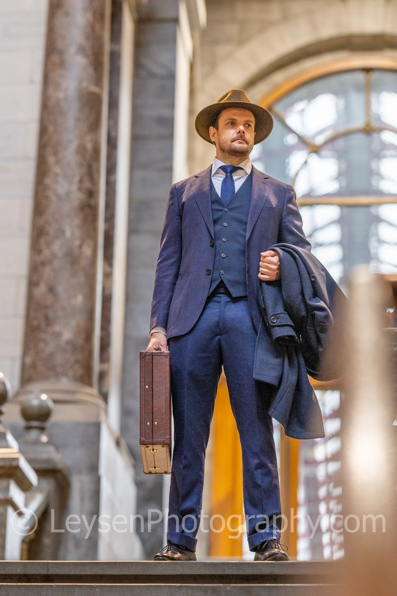 Executive businessman wearing hat walking through historic building