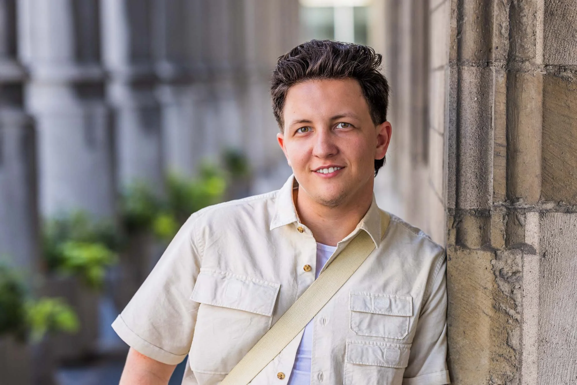 "Portretfoto van Alex Verspecht, leunend tegen een stenen zuil in het historisch centrum van Mechelen, aan het stadhuis genomen tijdens een lifestyle fotoshoot"