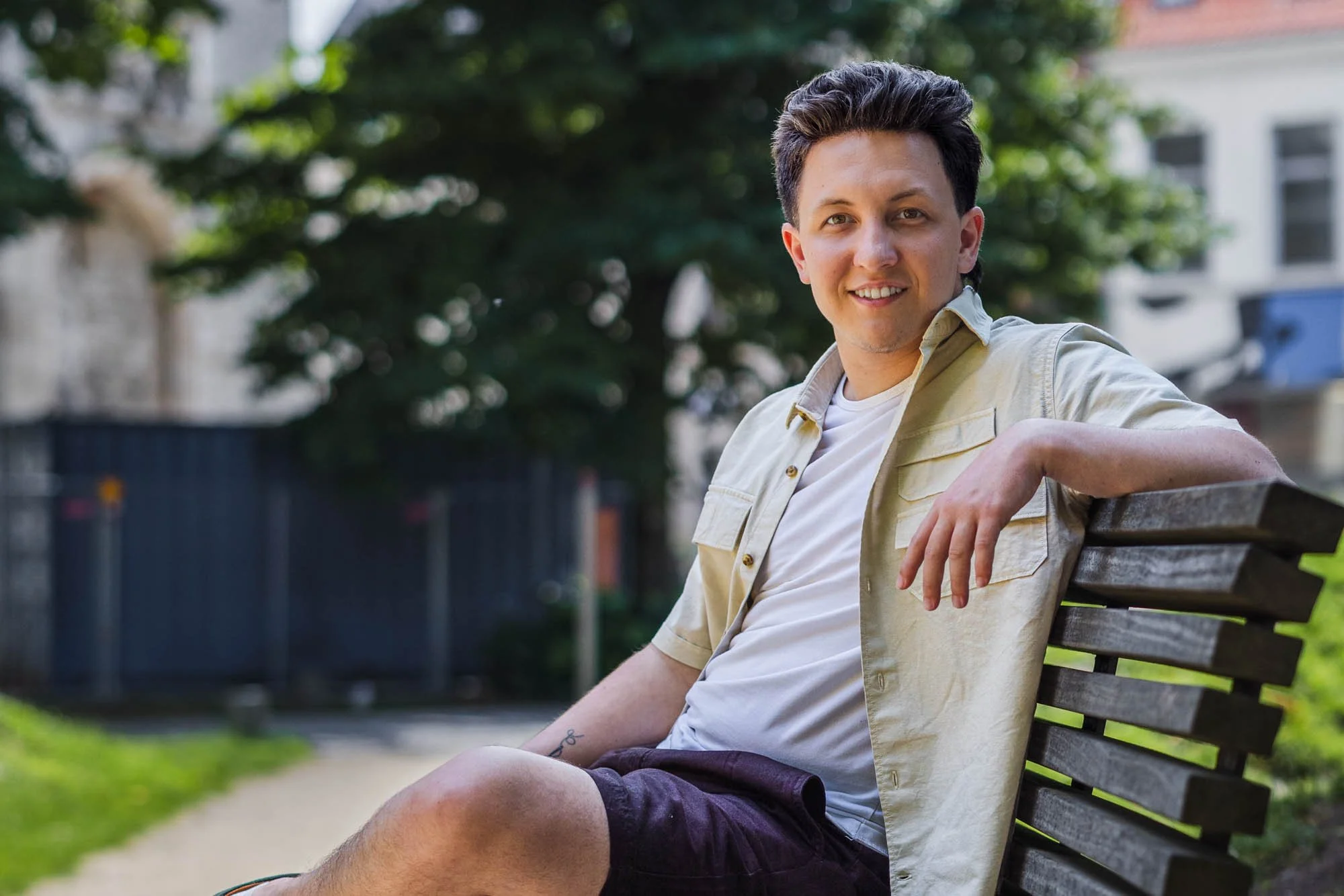 Alex Verspecht ontspannen zittend op een houten bank in een stadspark in Mechelen, kijkend naar de camera met open houding