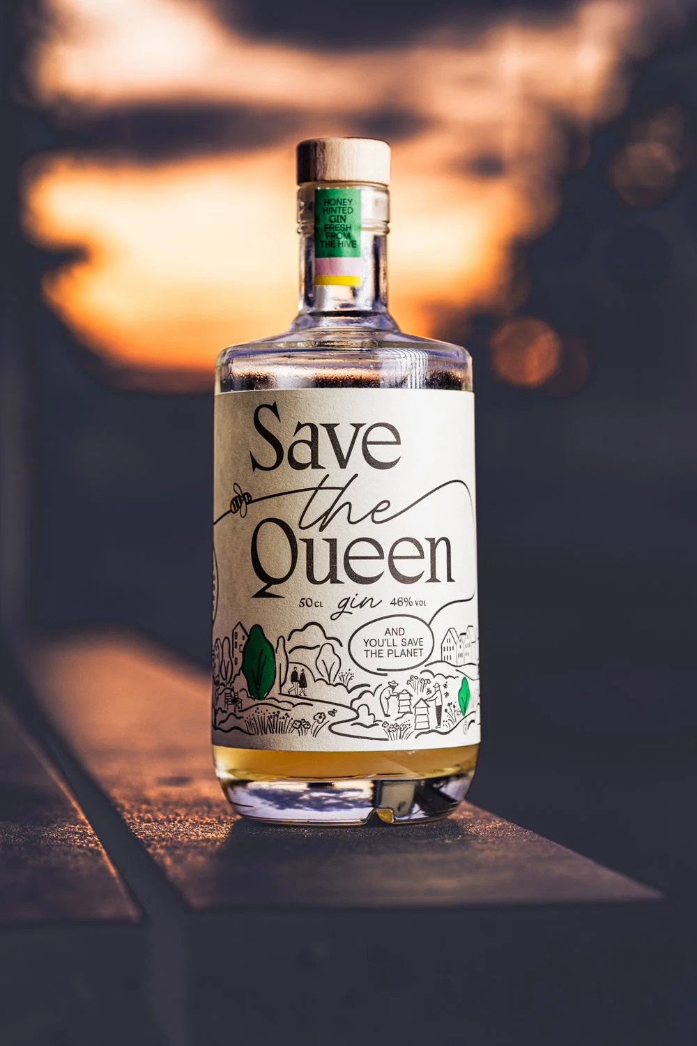 Bottle of Save the queen Gin, photographed on a wooden bench, while the sun is going under