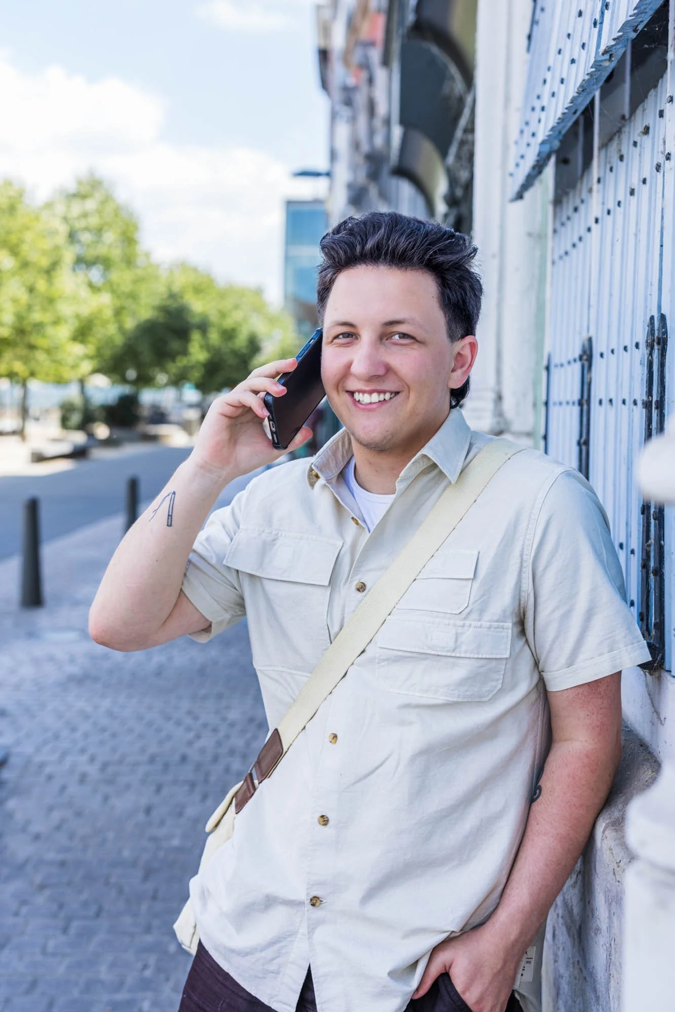 Halftotaal portret van Alex Verspecht leunend tegen een gevel terwijl hij telefoneert, in het centrum van Mechelen"