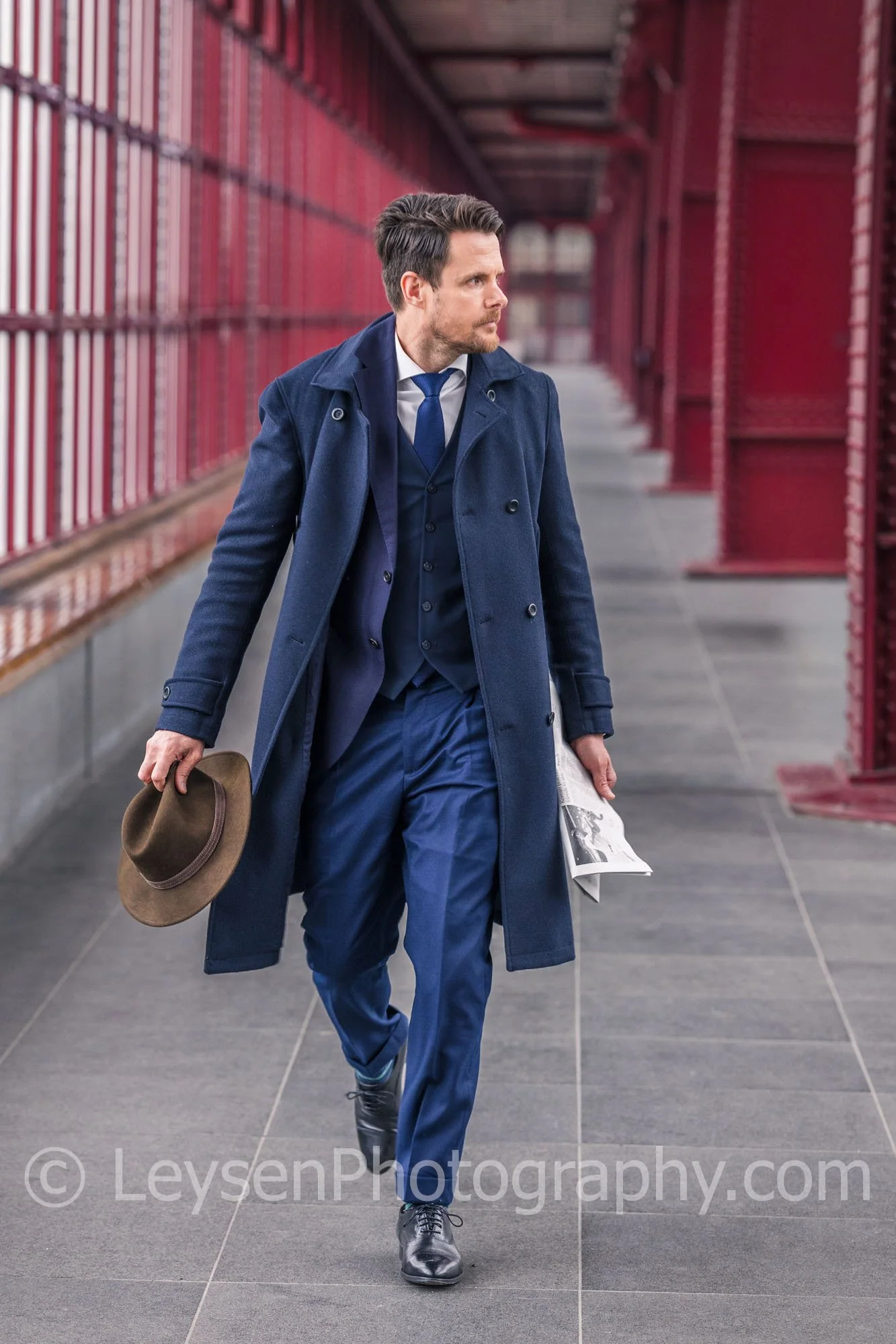 Businessman Walking with Hat and Newspaper in Urban Architecture
