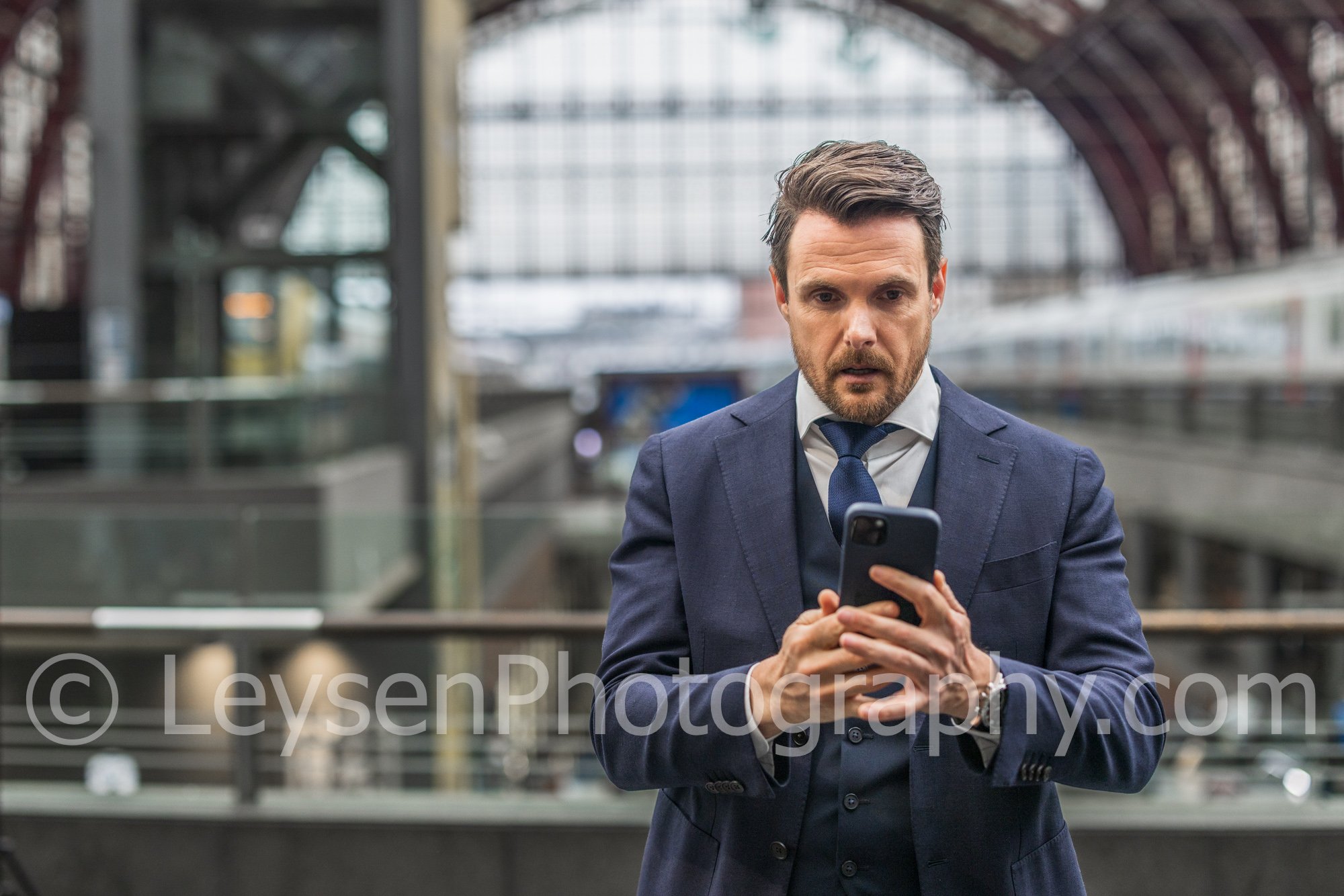 Businessman Looking at Smartphone in Train Station – Modern Business Lifestyle Photo