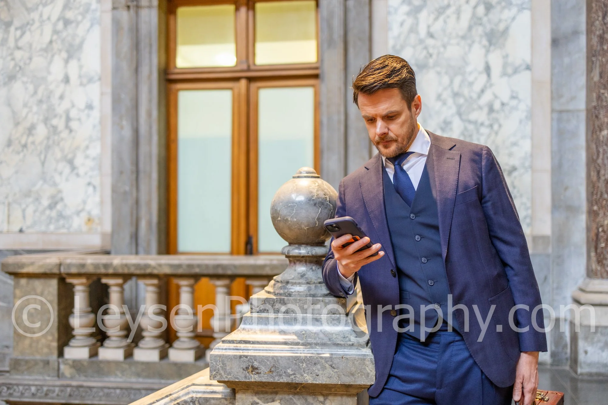 Businessman checking smartphone inside elegant historic building interior