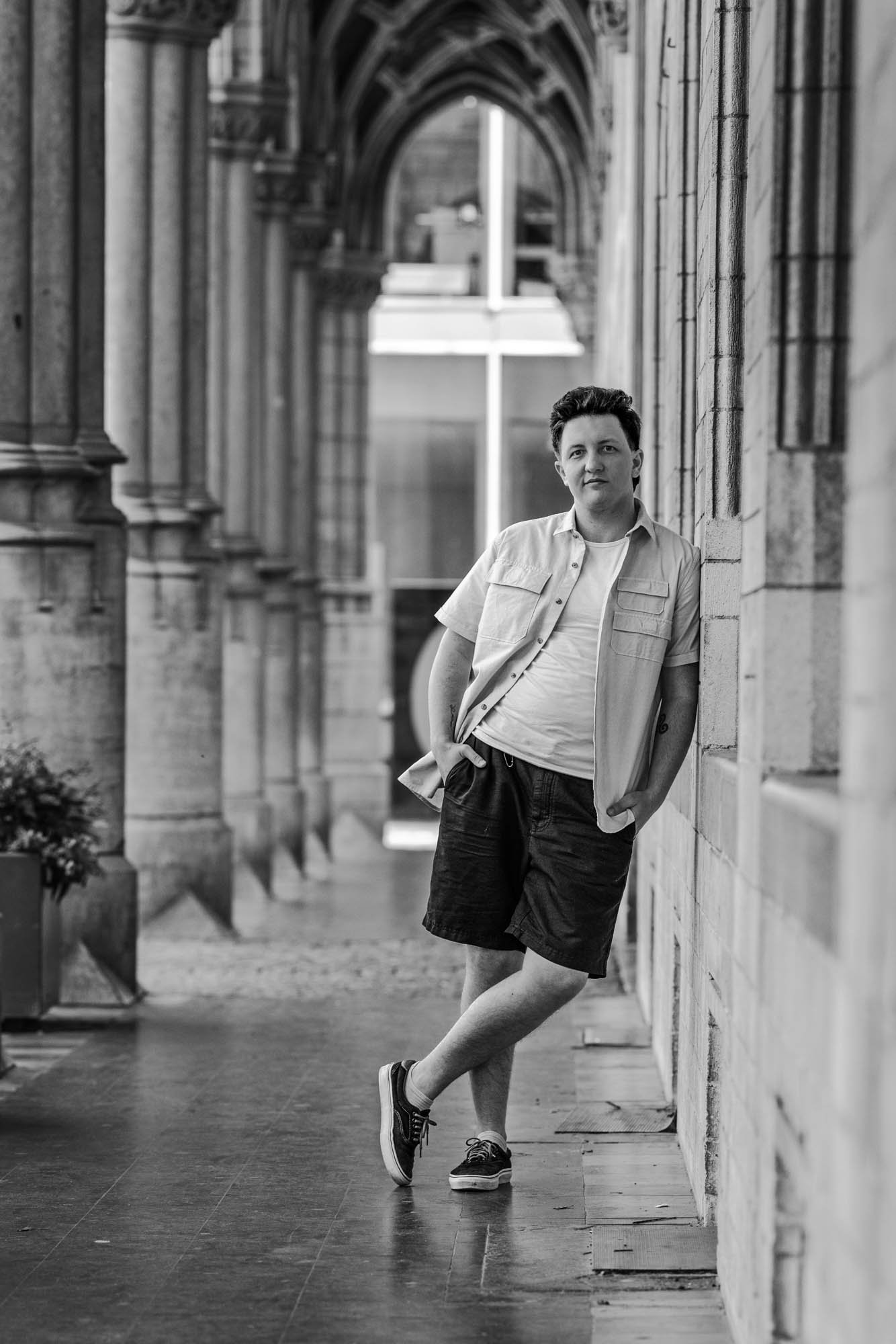 Artistiek lifestyle zwart wit portret van Alex verspecht. man kijkt leunend tegen de gevel recht naar de camera op een wat relaxte wijze, terwijl hij zijn handen in zijn zakken heeft.
locatie: historisch Stadhuis van Mechelen