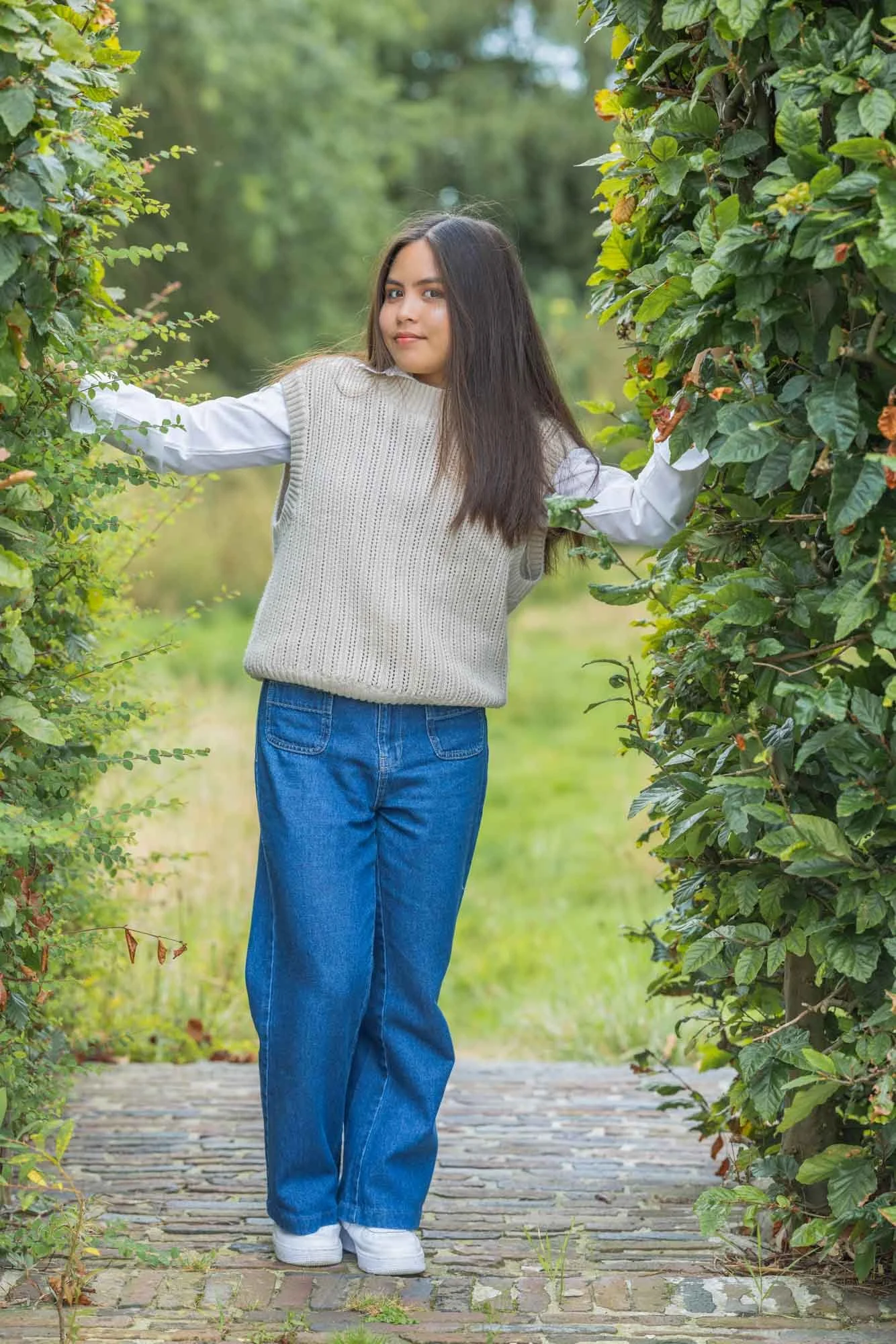 Professioneel portret Mechelen – vrouw tussen groene hagen, open houding en natuurlijke connectie met de omgeving
