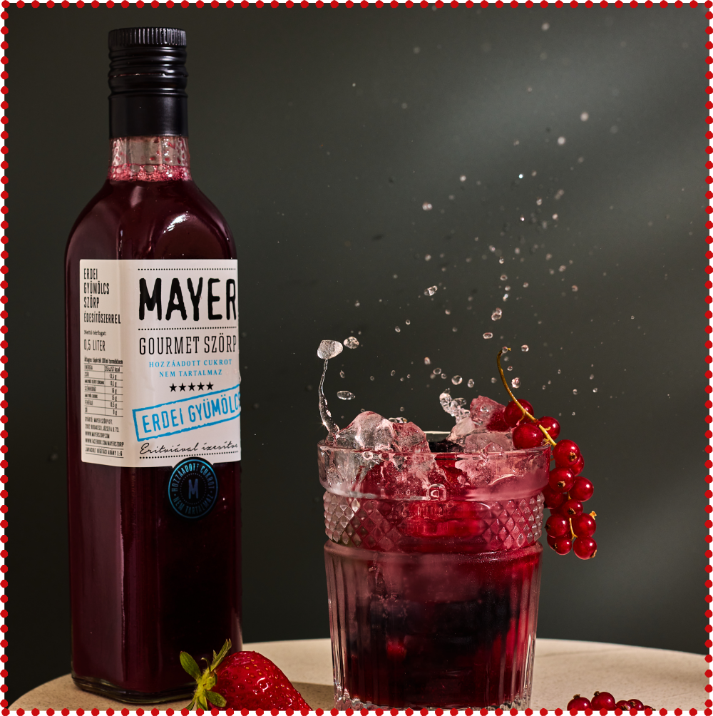 A bottle of Mayer Gourmet Szorp hot sauce with a white label and blue accents, lying on a pink textured surface.