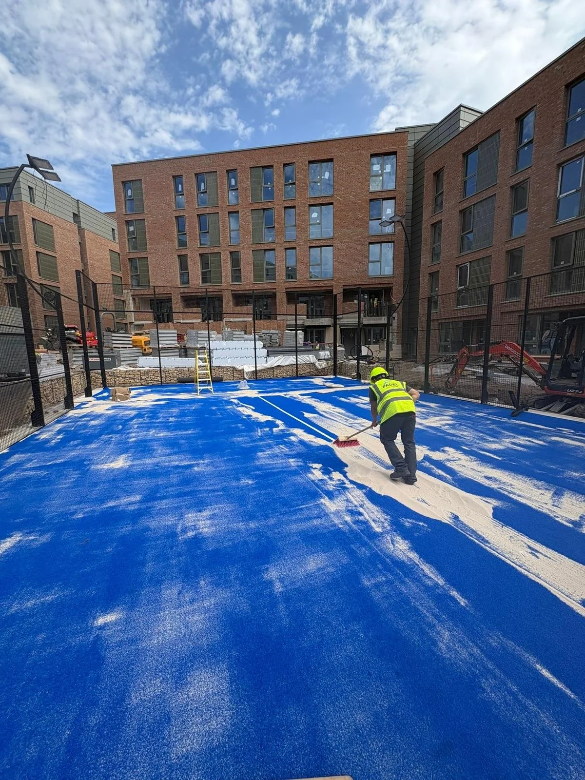 Construction worker in high-visibility vest Sanding a new Padel Court in the UK with Sound proofing for Padel