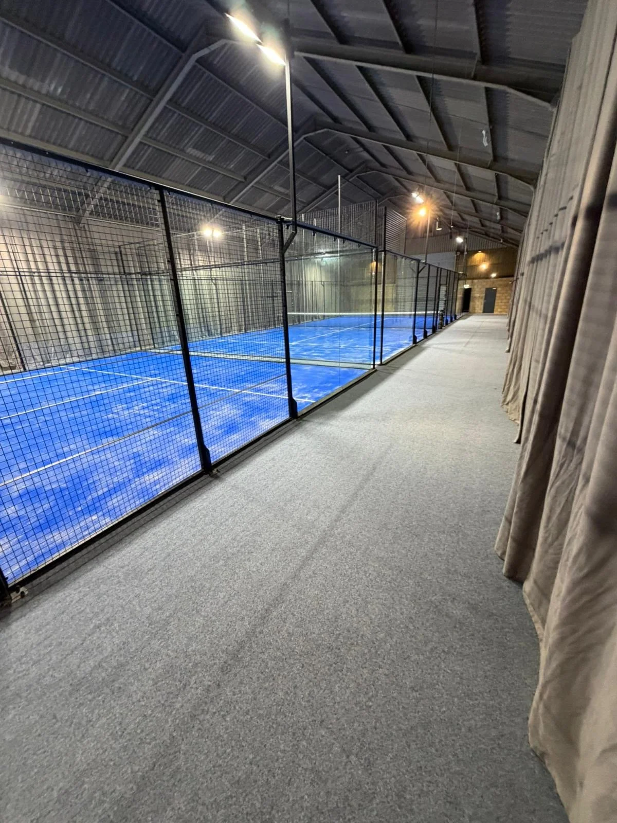 Indoor Padel Court inside a converted barn. With grey carpet and curtains to absorb noise