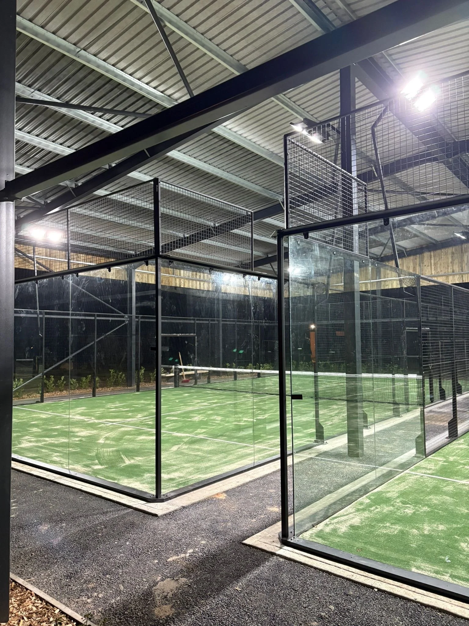 Indoor Padel Court underneath a canopy at night, with lights.
