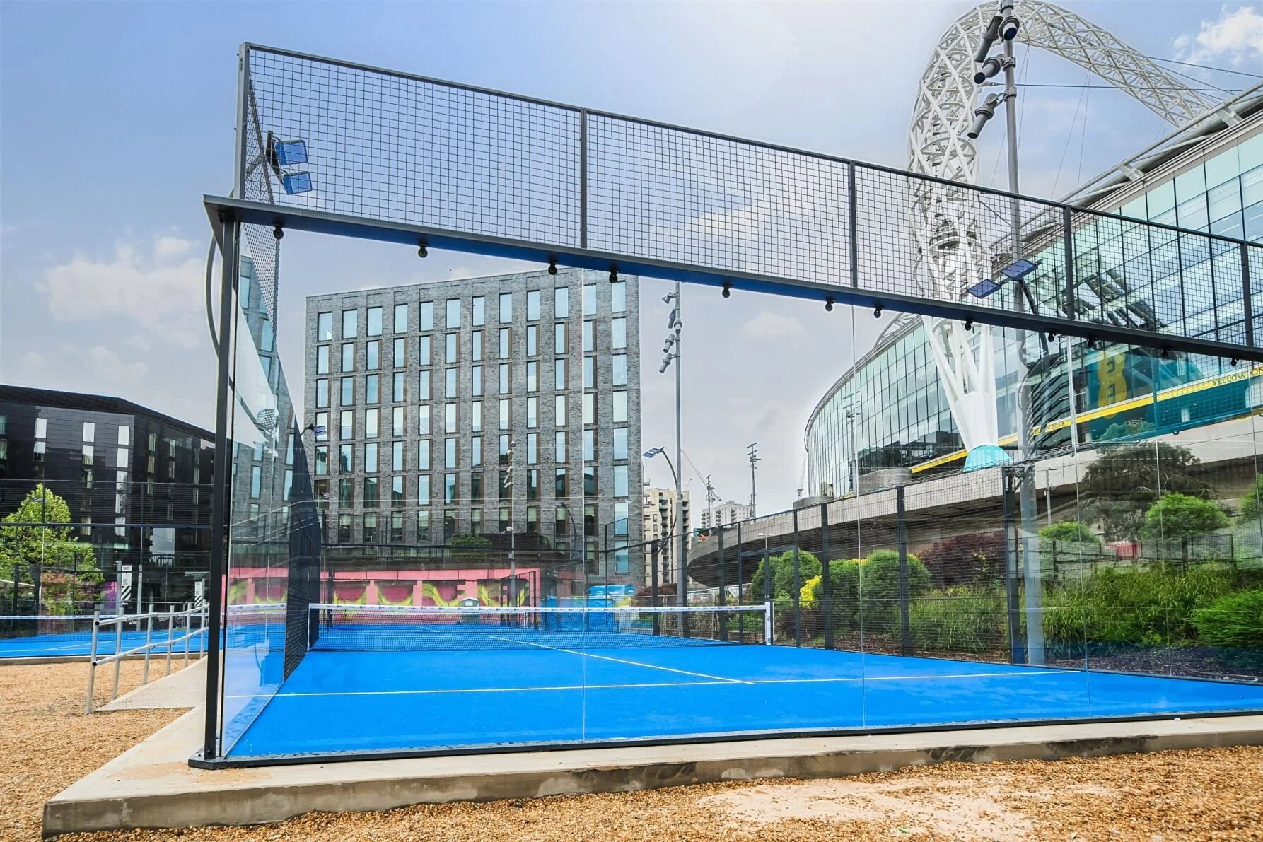 An outdoor padel tennis court with a blue playing surface at Wembley Stadium. UKs best Padel Courts