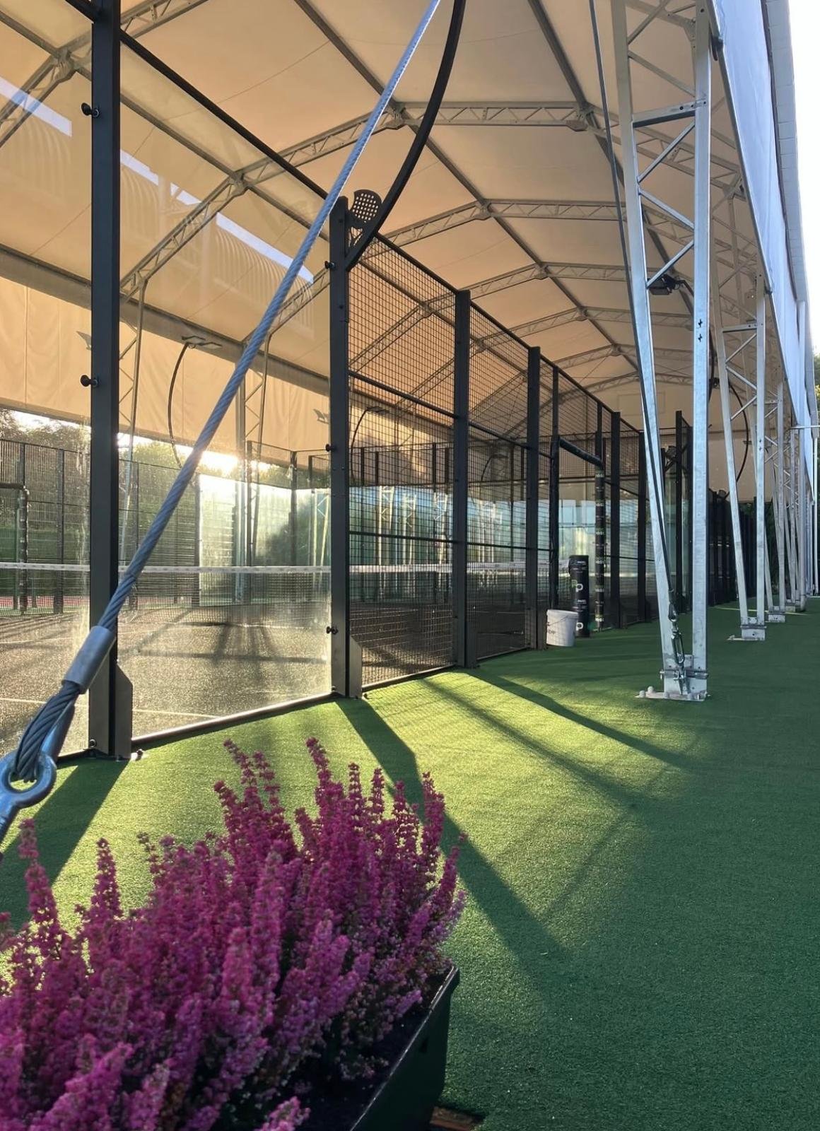 An outdoor Padel Court under a Canopy in the UK. 2 Courts with Black Turf and green perimiter turf. Padel Pass Luton