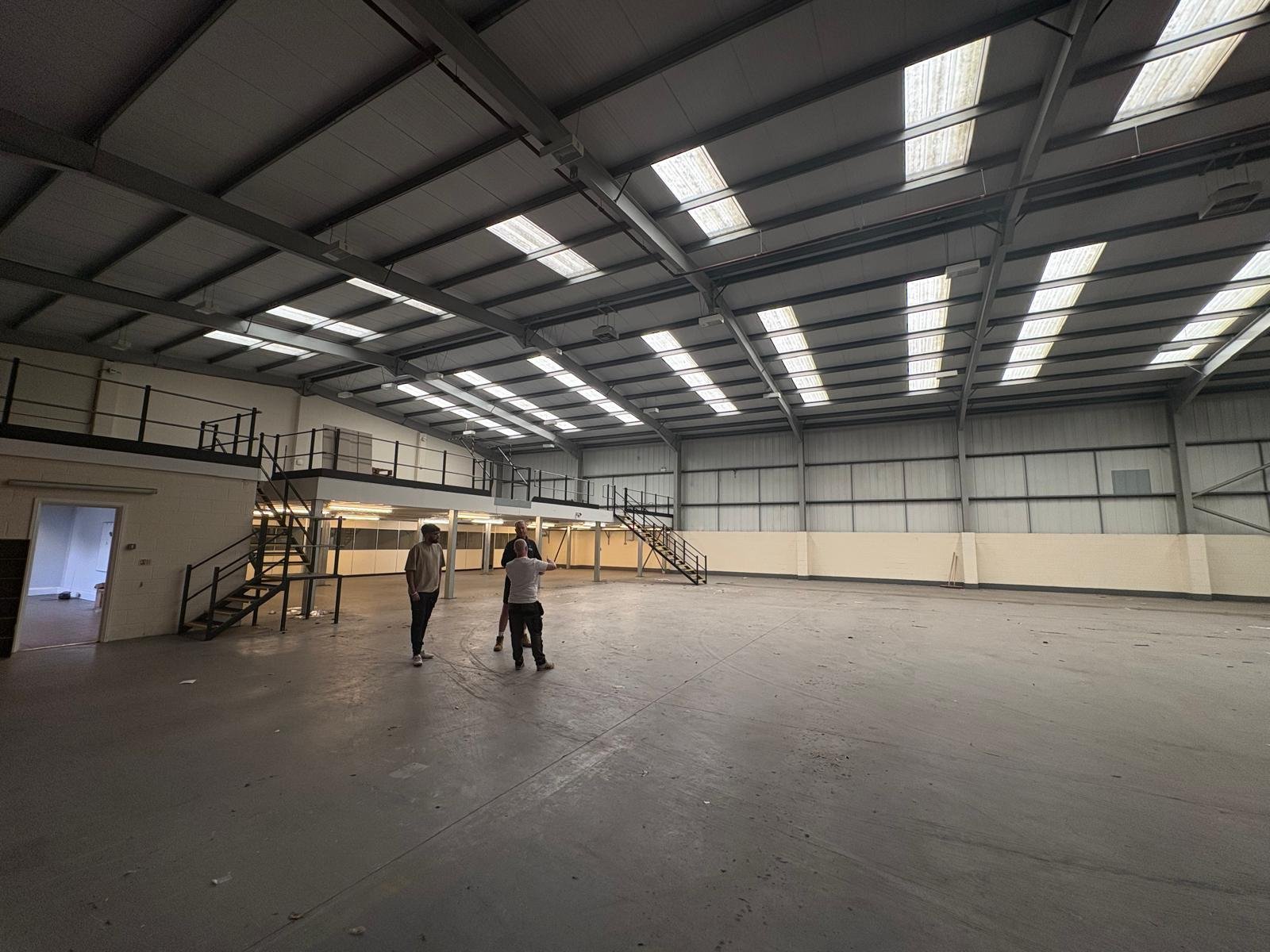 A spacious, empty industrial warehouse with high metal ceiling being measured to test feasibility for Padel. Padel Studios Coventry.