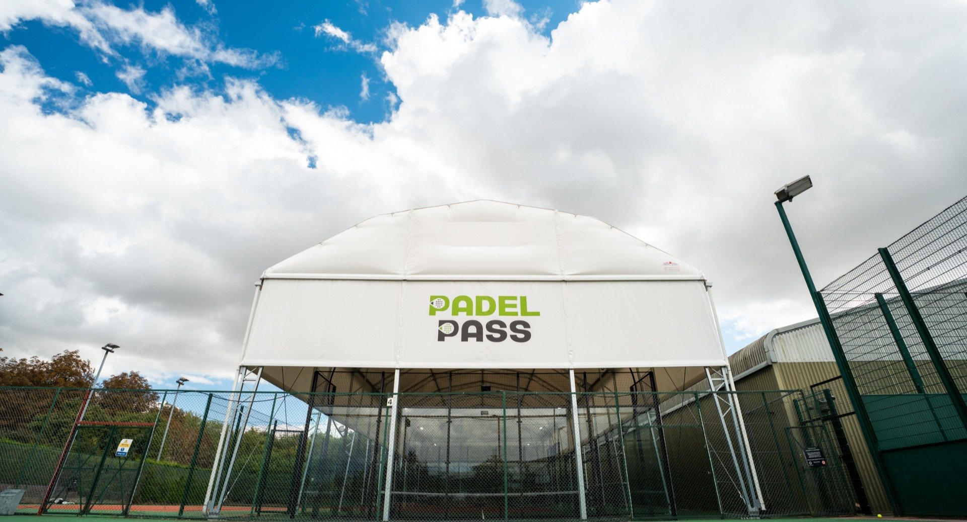 A Padel facility with a white canopy featuring the text 'PADEL PASS' in green and black.