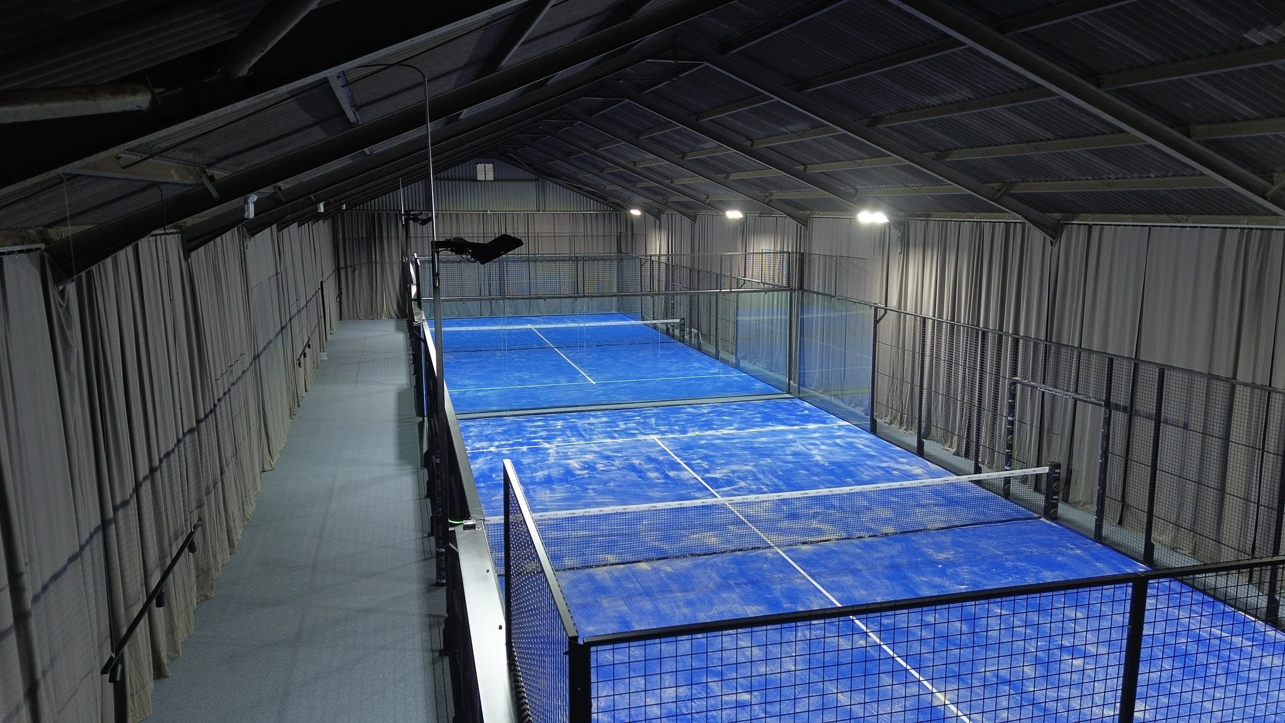 Two Indoor Padel Courts with blue turf in a converted Barn. Podington Padel Uk
