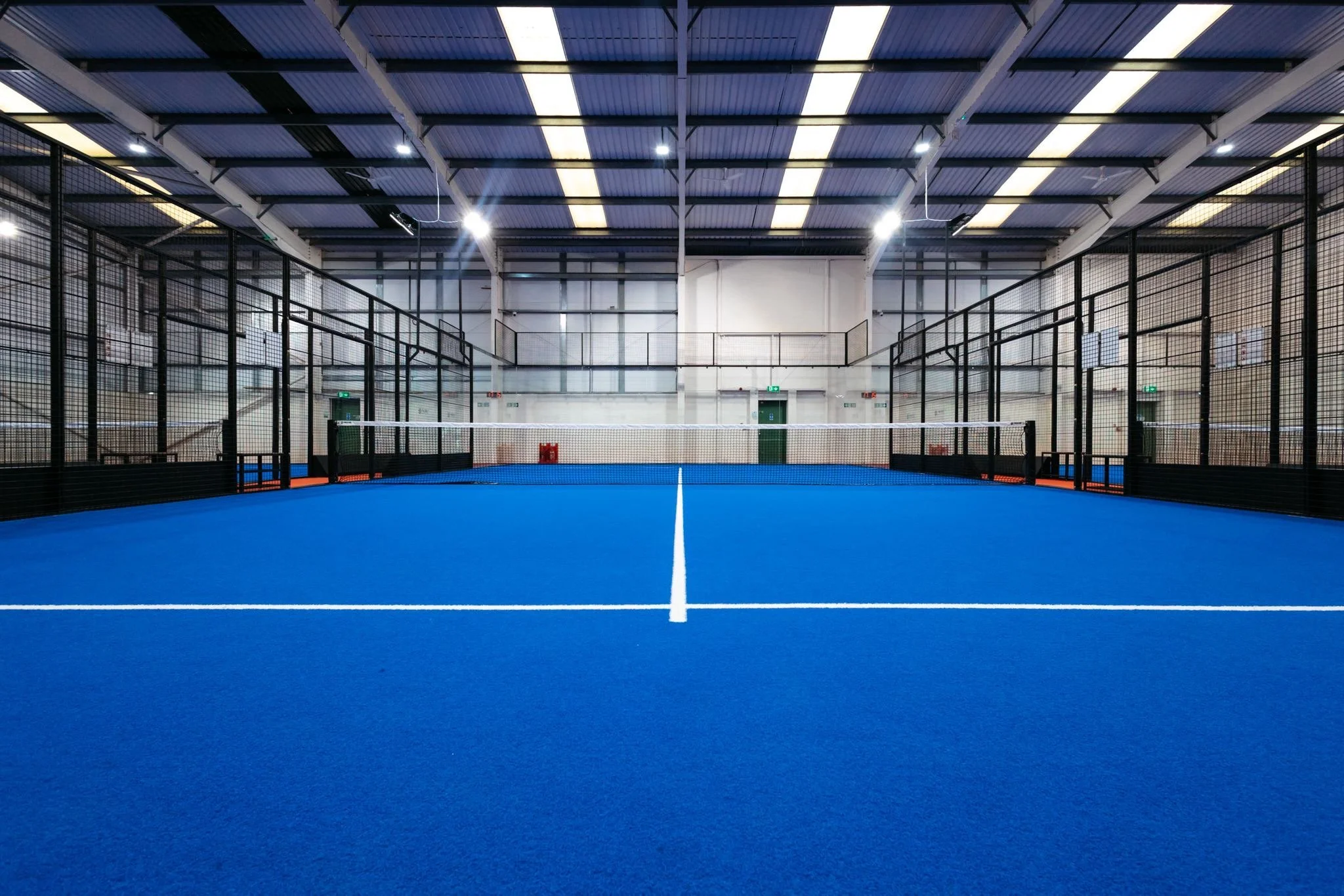 Full Panoramic Padel Court with blue turf indoors in a warehouse. UKs best Padel Court suppliers