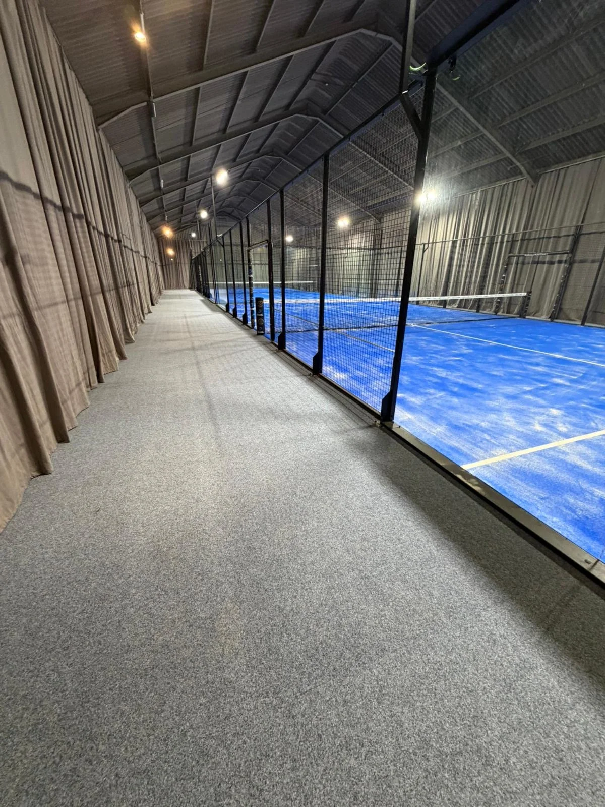 Indoor Padel Court inside a converted barn. With grey carpet and curtains to absorb noise