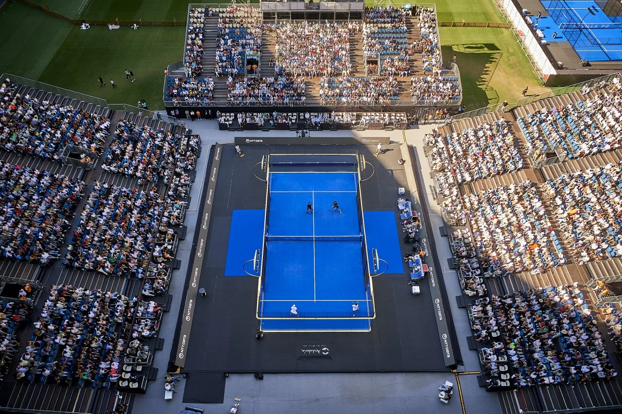 An aerial view of a professional Padel court, in a stadium filled with spectators