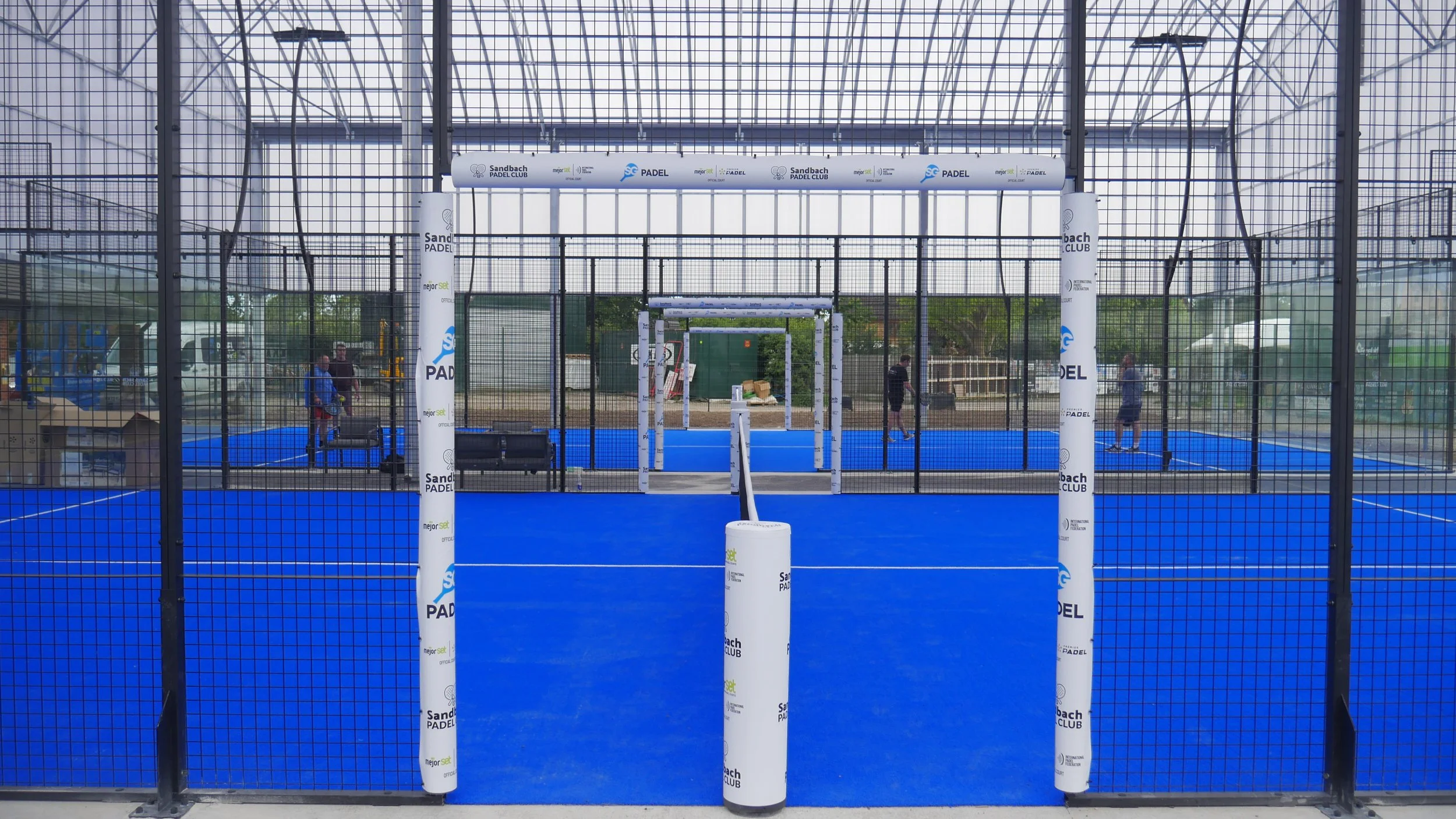 A Padel Complex underneath a large Canopy. Blue surface and White protective Covers.