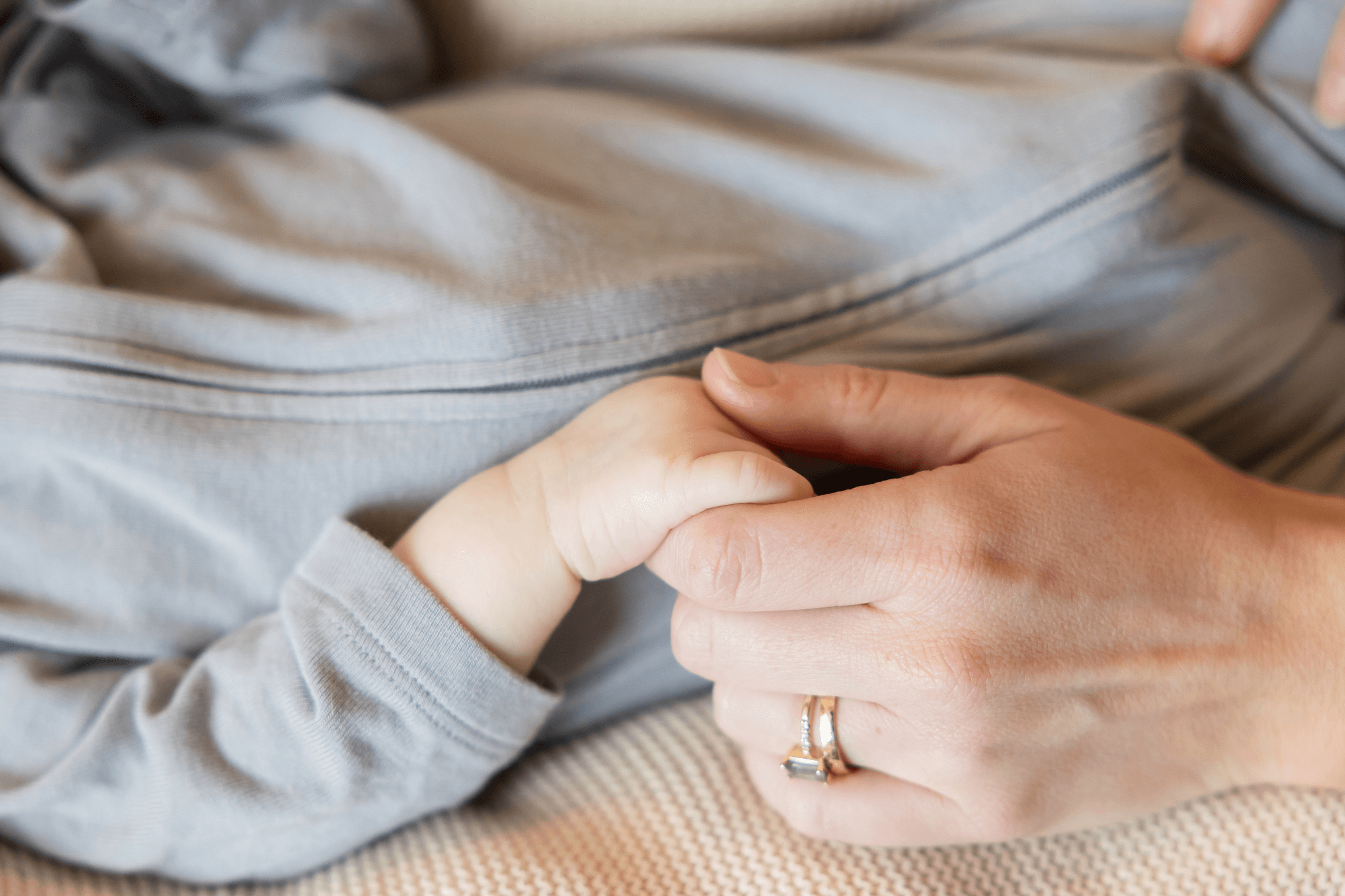A mom holds her baby's hand, navigating life after the NICU with a doula recommended by The NICU Translator.