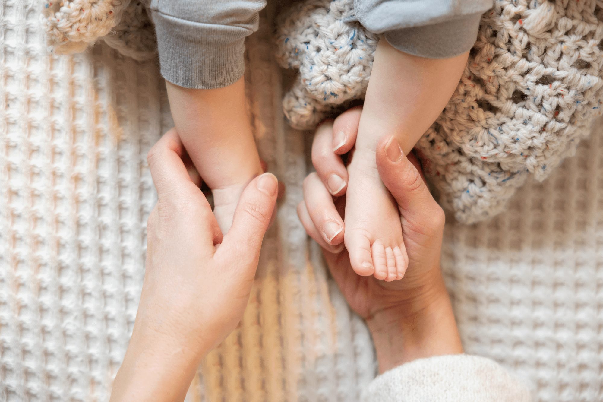 A mother receives preemie support from The NICU Translator while holding her baby's feet.