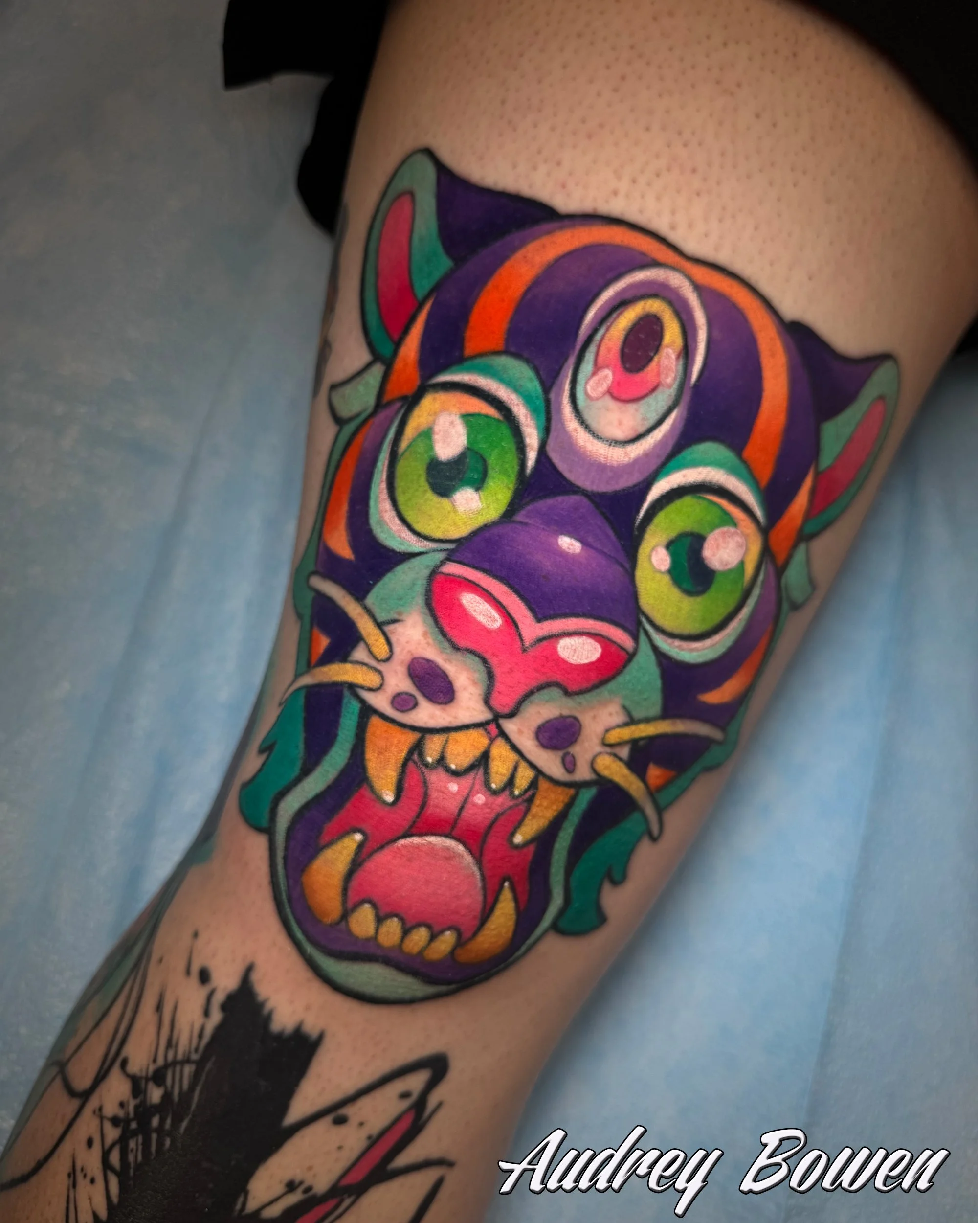 A colorful tattoo of a panther with flames and abstract designs on a person's arm. Tattoo by Audrey Bowen, Karmic Tattoo, Clearwater Florida