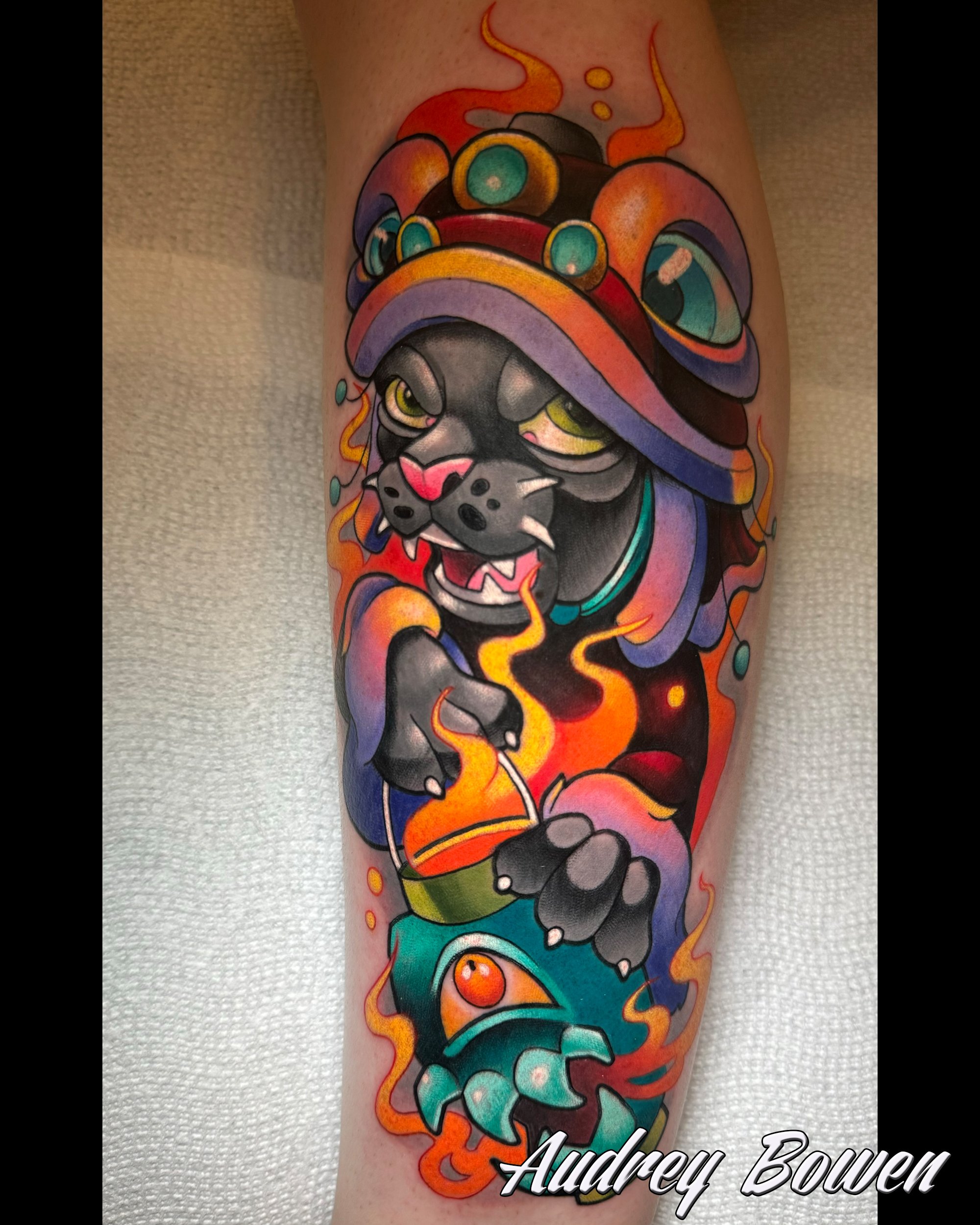 Colorful tattoo of a stylized panther with a multicolored headdress, flames, and abstract shapes on the arm. Tattoo by Audrey Bowen, Karmic Tattoo, Clearwater Florida