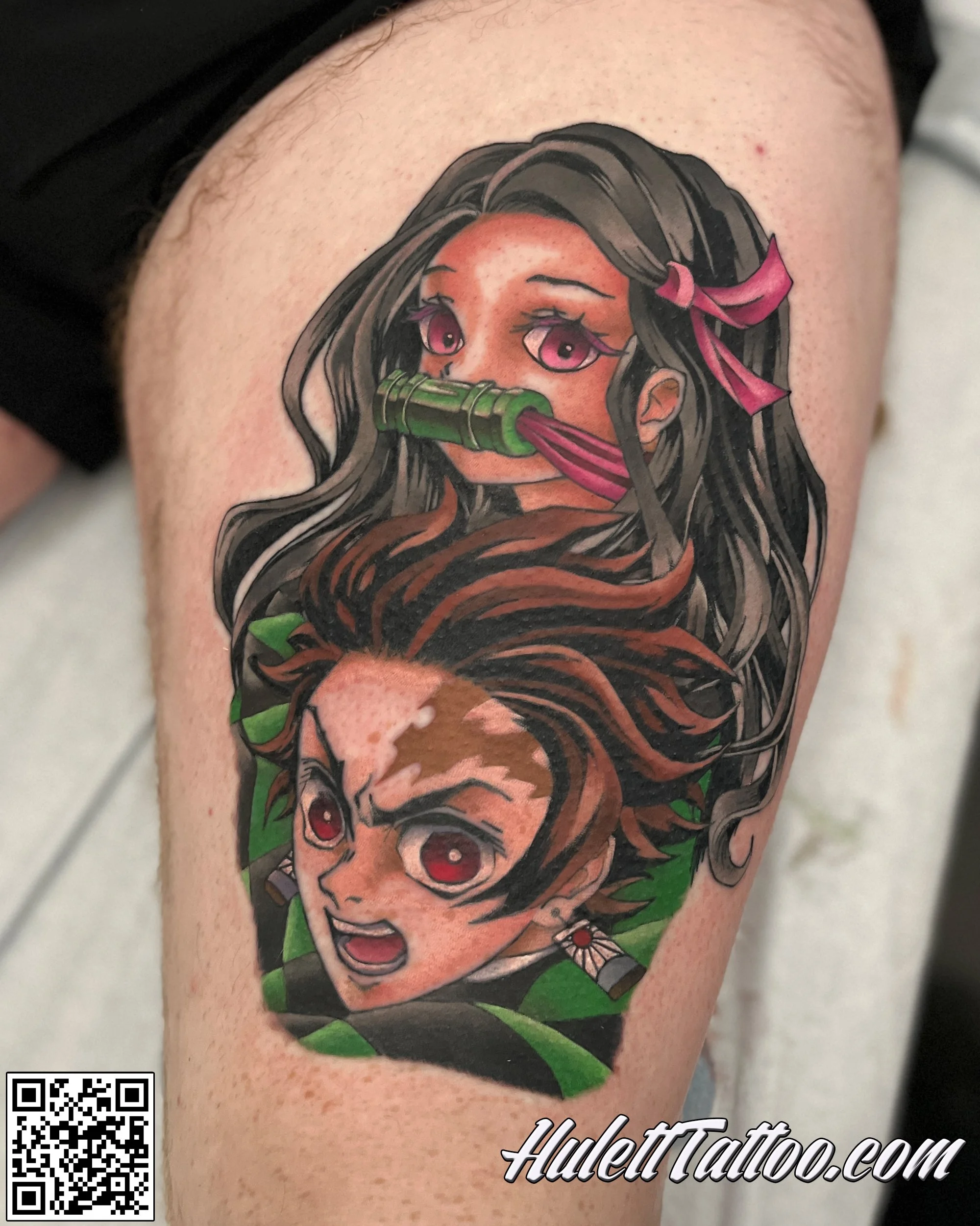 Tattoo of two anime characters with intense expressions, one with long dark hair and pink ribbons and the other with short brown hair, both with striking red eyes and green foliage in the background.