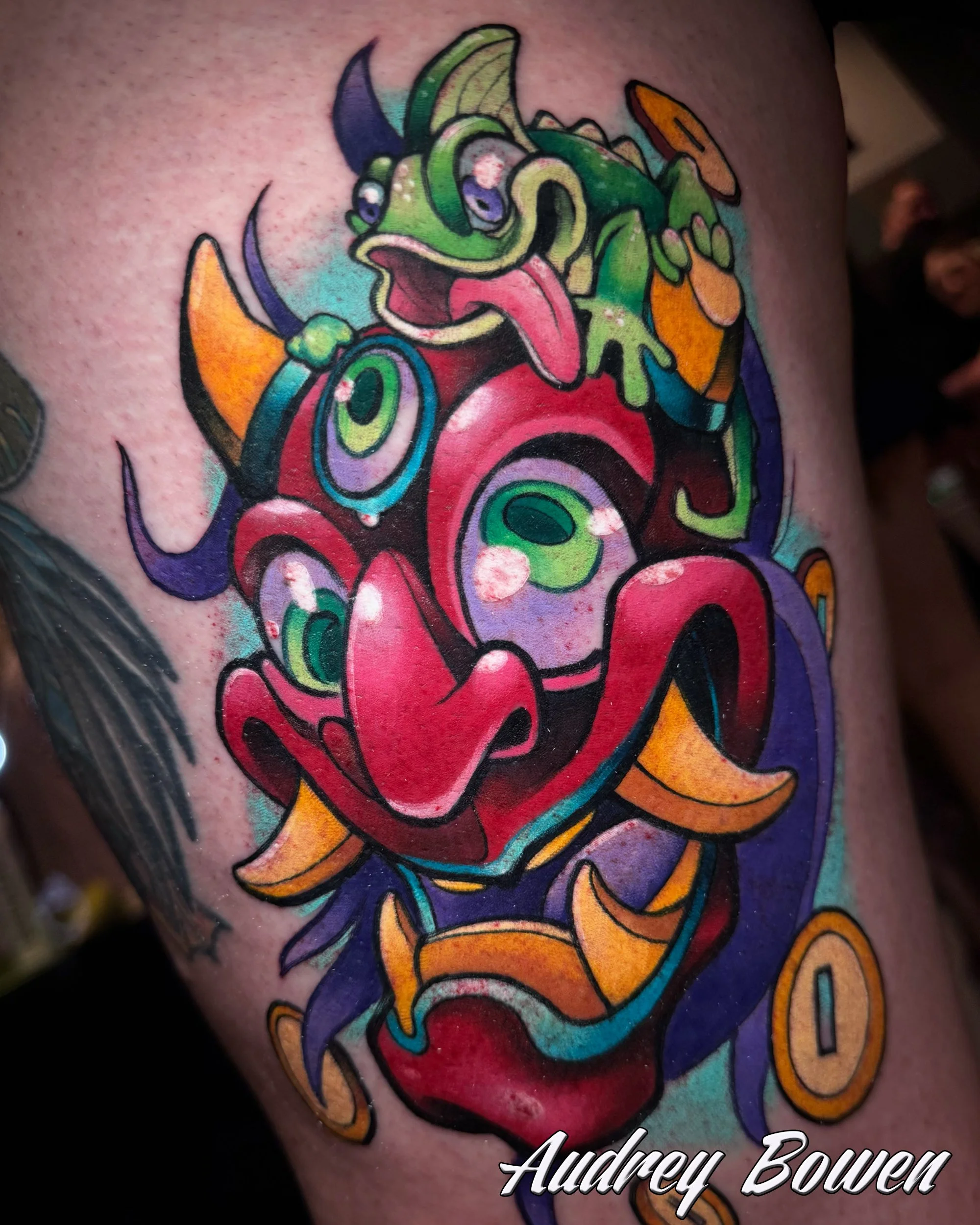 Colorful tattoo of a cartoonish Japanese Oni Mask. Tattoo by Audrey Bowen, Karmic Tattoo, Clearwater Florida
