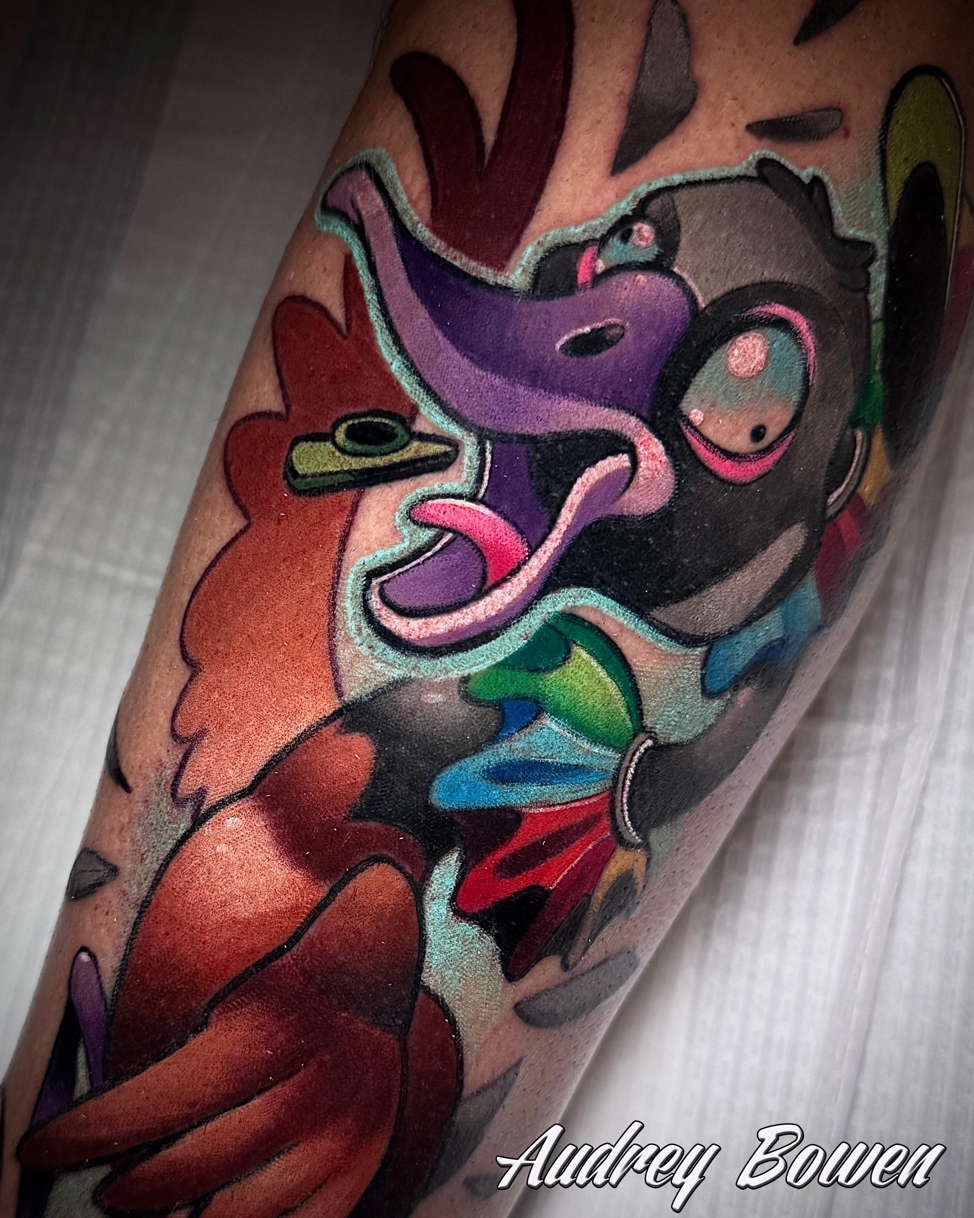 Close-up of a colorful tattoo of a silly goose, featuring abstract and cartoon-like characters with bold outlines, vibrant colors. Tattoo by Audrey Bowen, Karmic Tattoo, Clearwater Florida