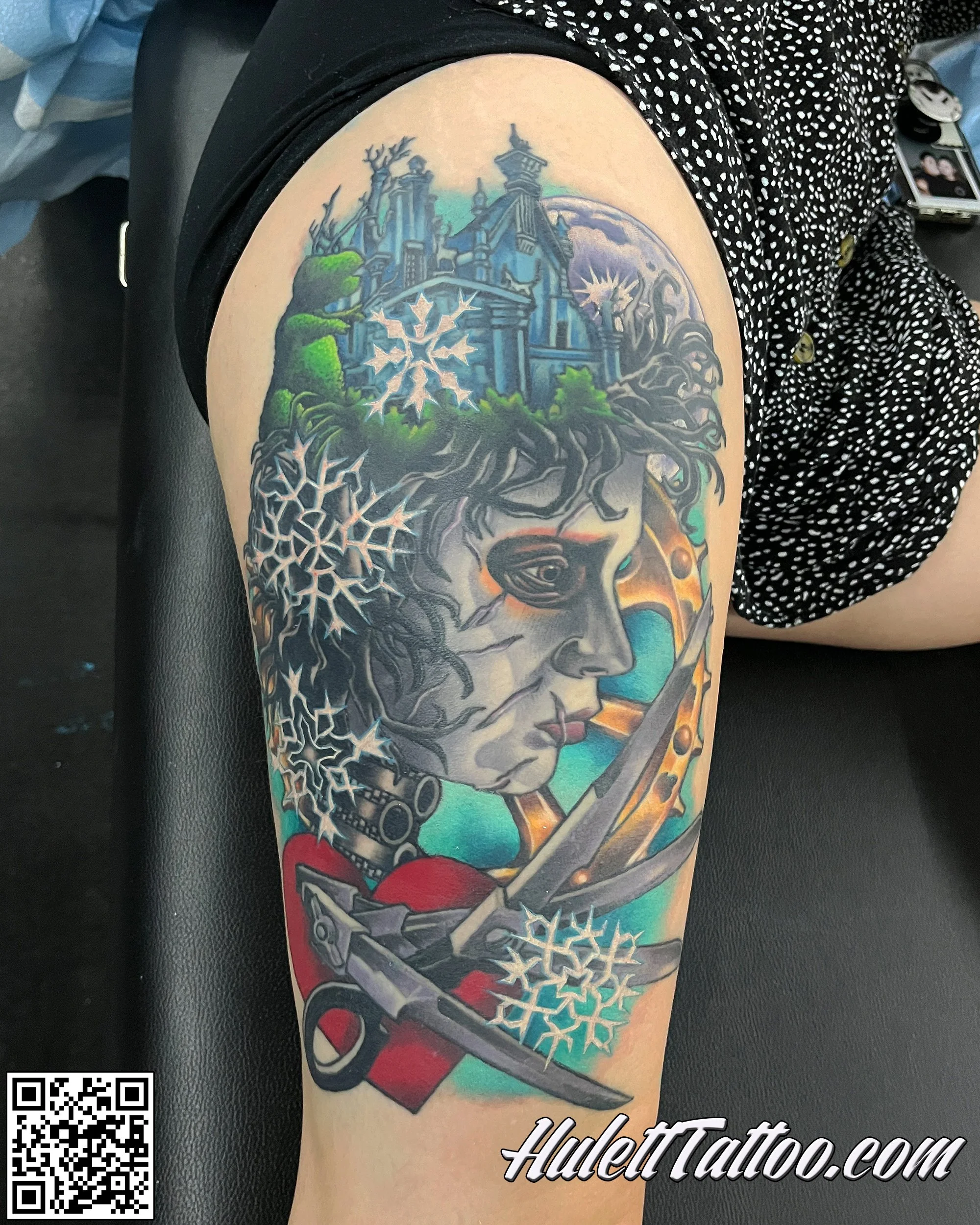 Colorful tattoo of an Edward Scissor's hand, Tim Burton. Surrounding are snowflakes, a castle on a hill, trees, a full moon.