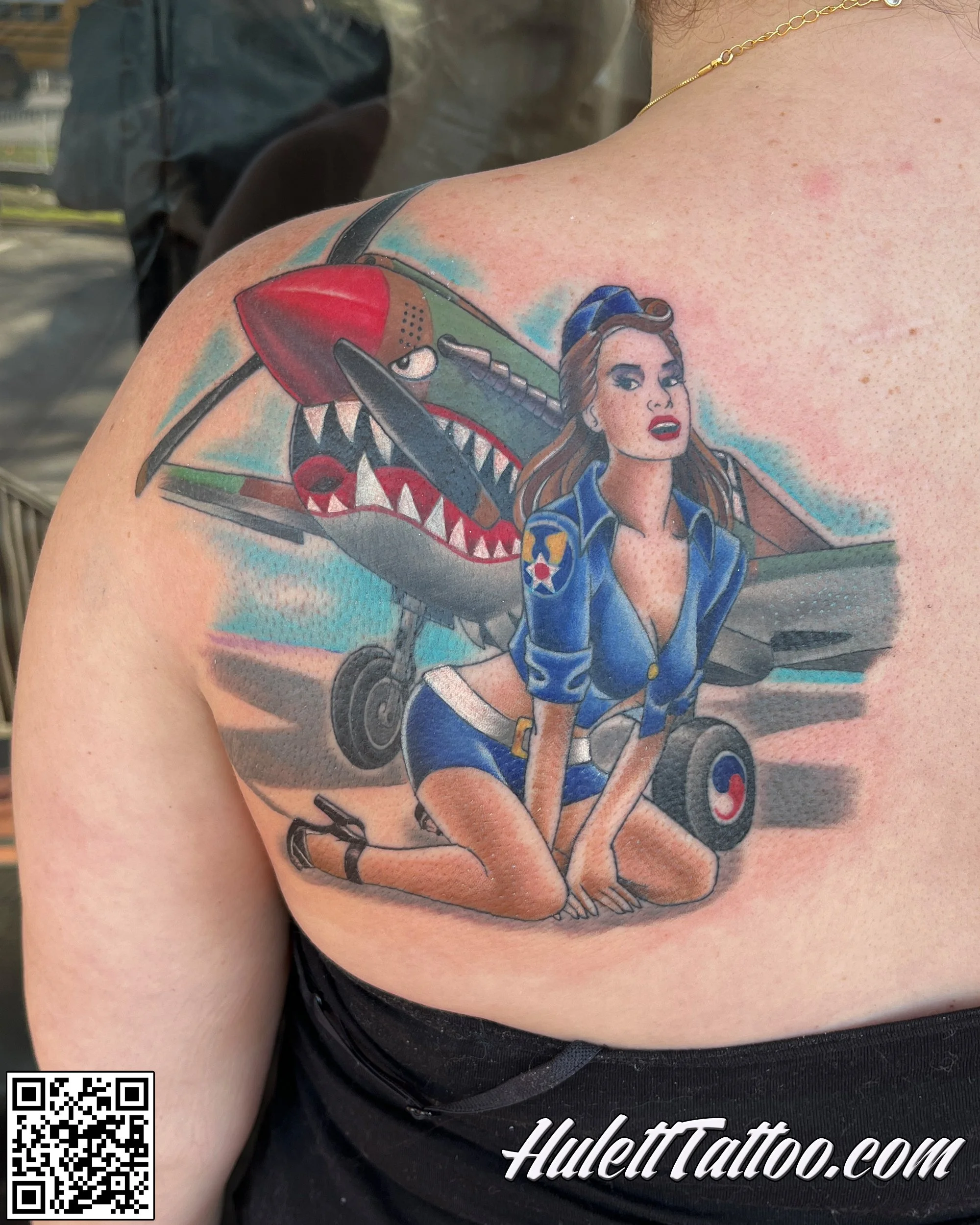 Colorful tattoo of a classic pin up bomber in front of a classic dog fighting plane from world war 2.