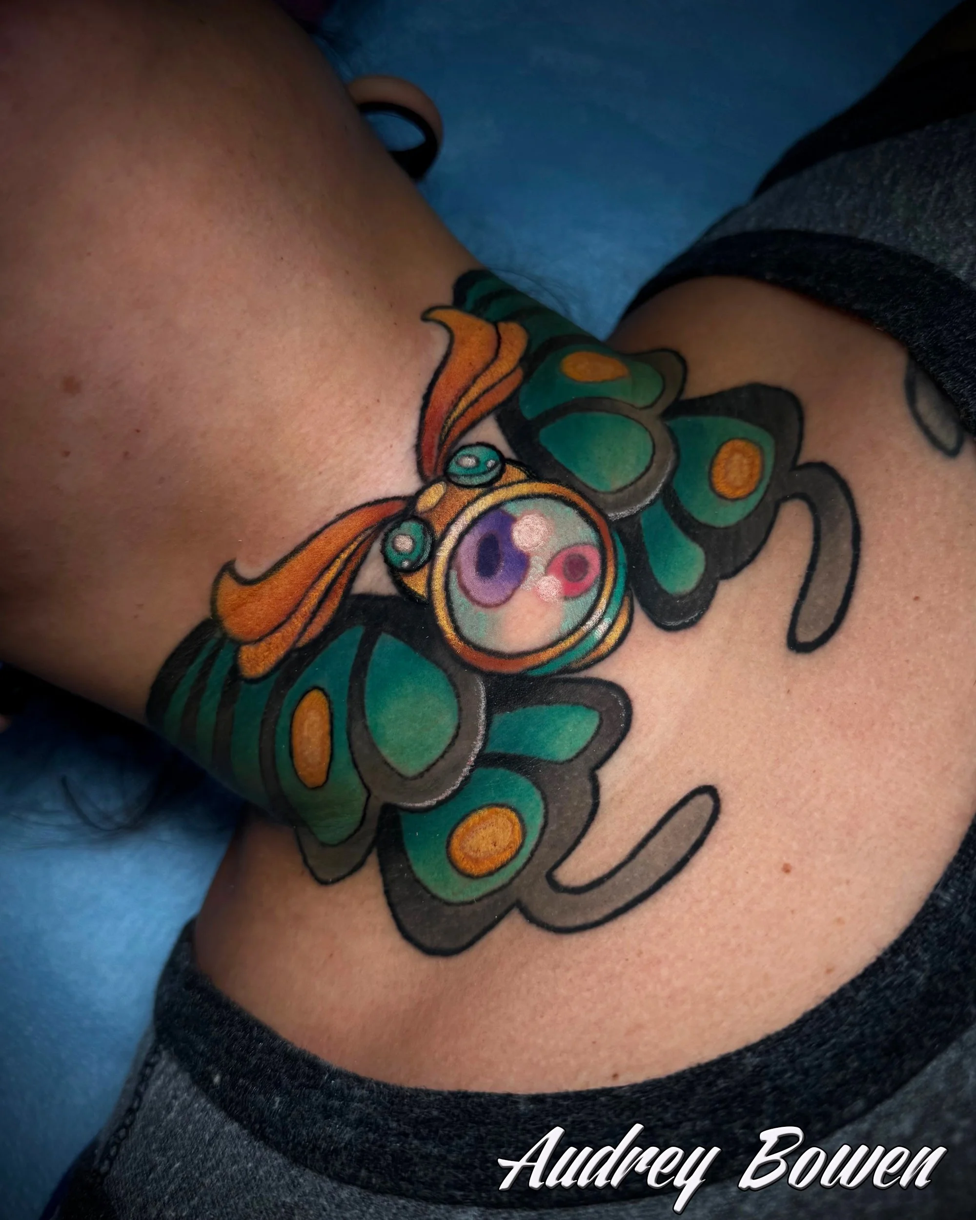 Close-up of a person's neck tattoo area showcasing a colorful butterfly tattoo with intricate details and vibrant colors. Tattoo by Audrey Bowen, Karmic Tattoo, Clearwater Florida