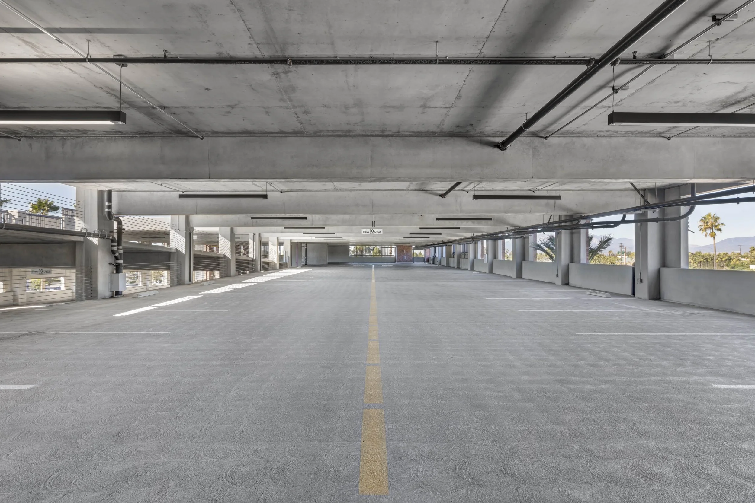 Empty multi-level parking garage with concrete ceiling and yellow line down the center.