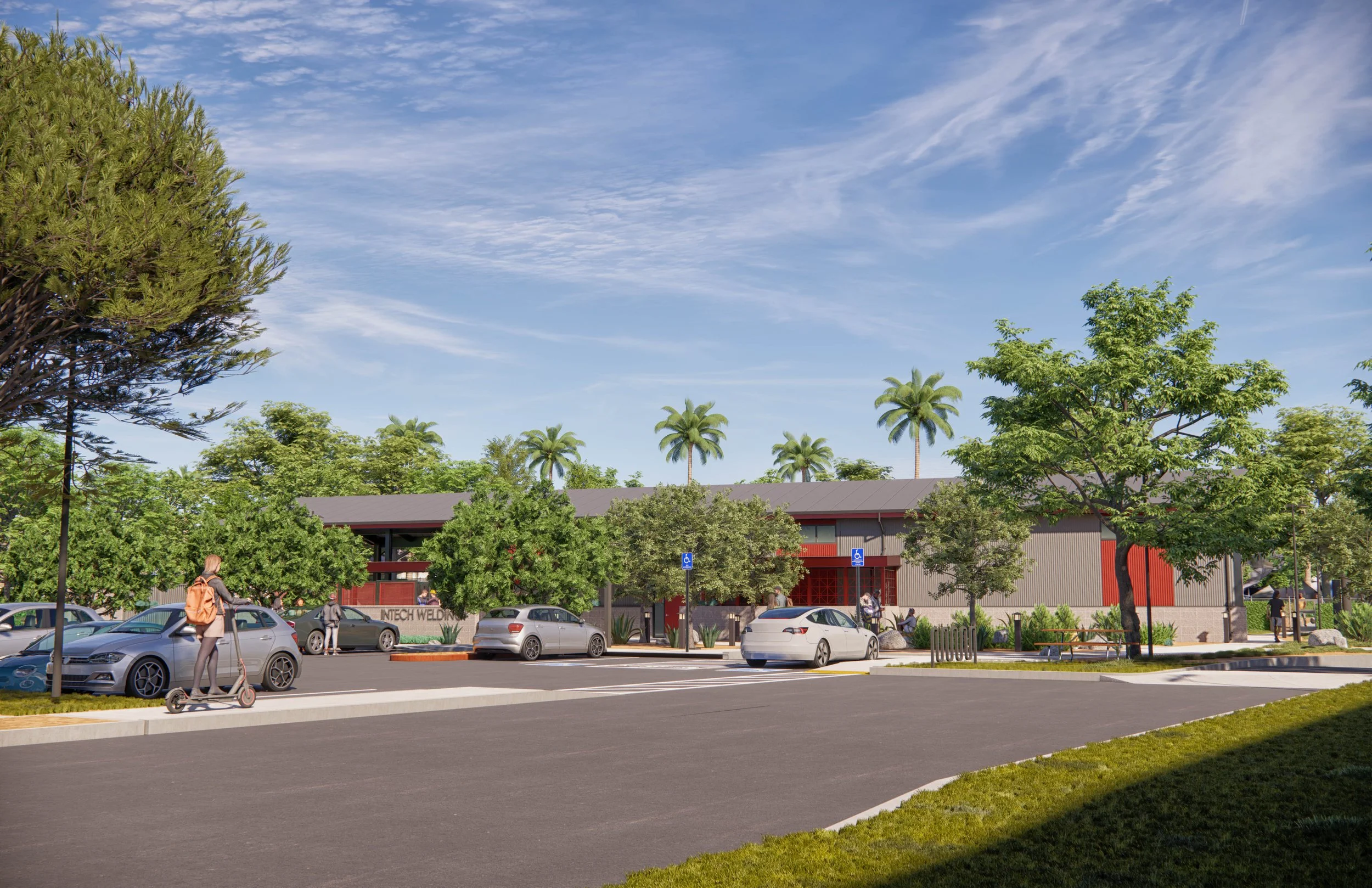 Parking lot with parked cars, trees, and a building in the background under a blue sky with scattered clouds.