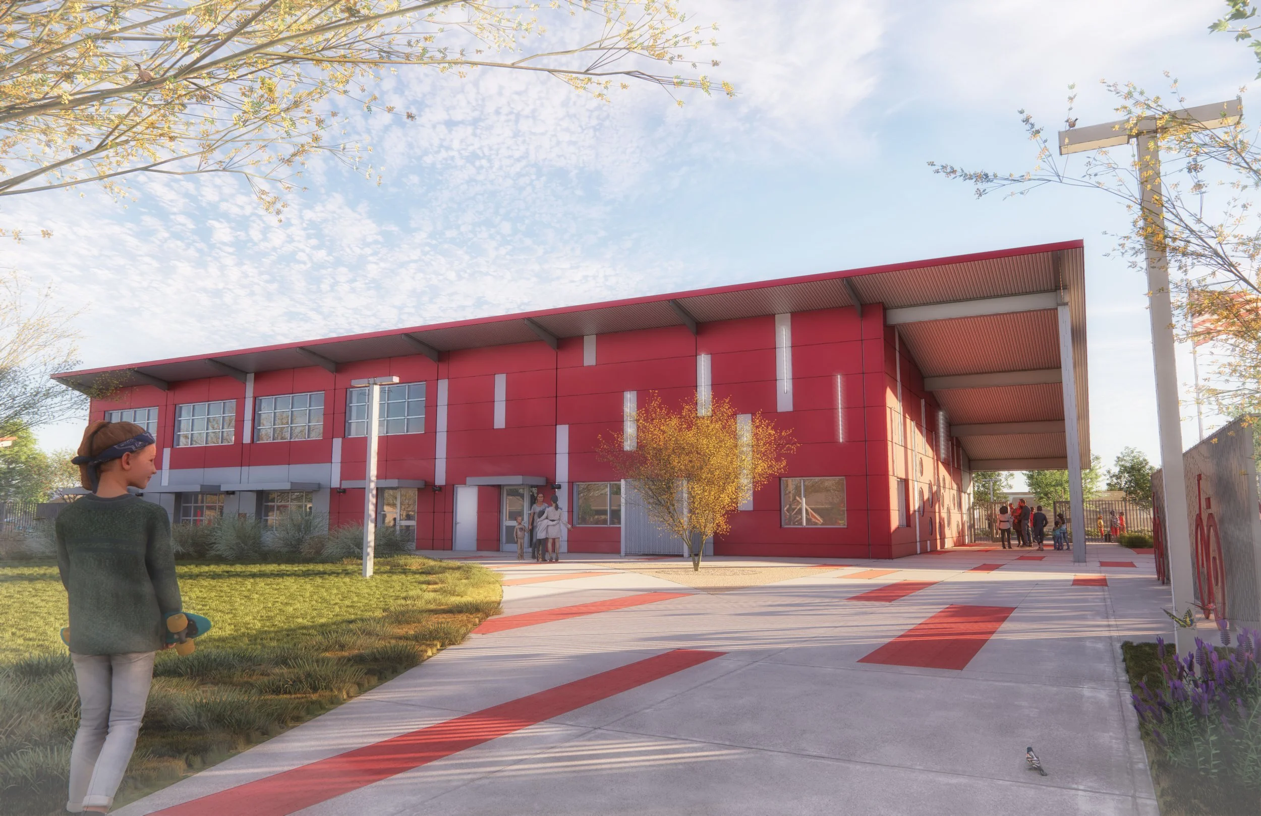 A modern school building with a red facade and large windows, surrounded by a landscaped area with trees, grass, and a paved walkway. Children and adults are visible outside, some walking and others talking near the entrance.
