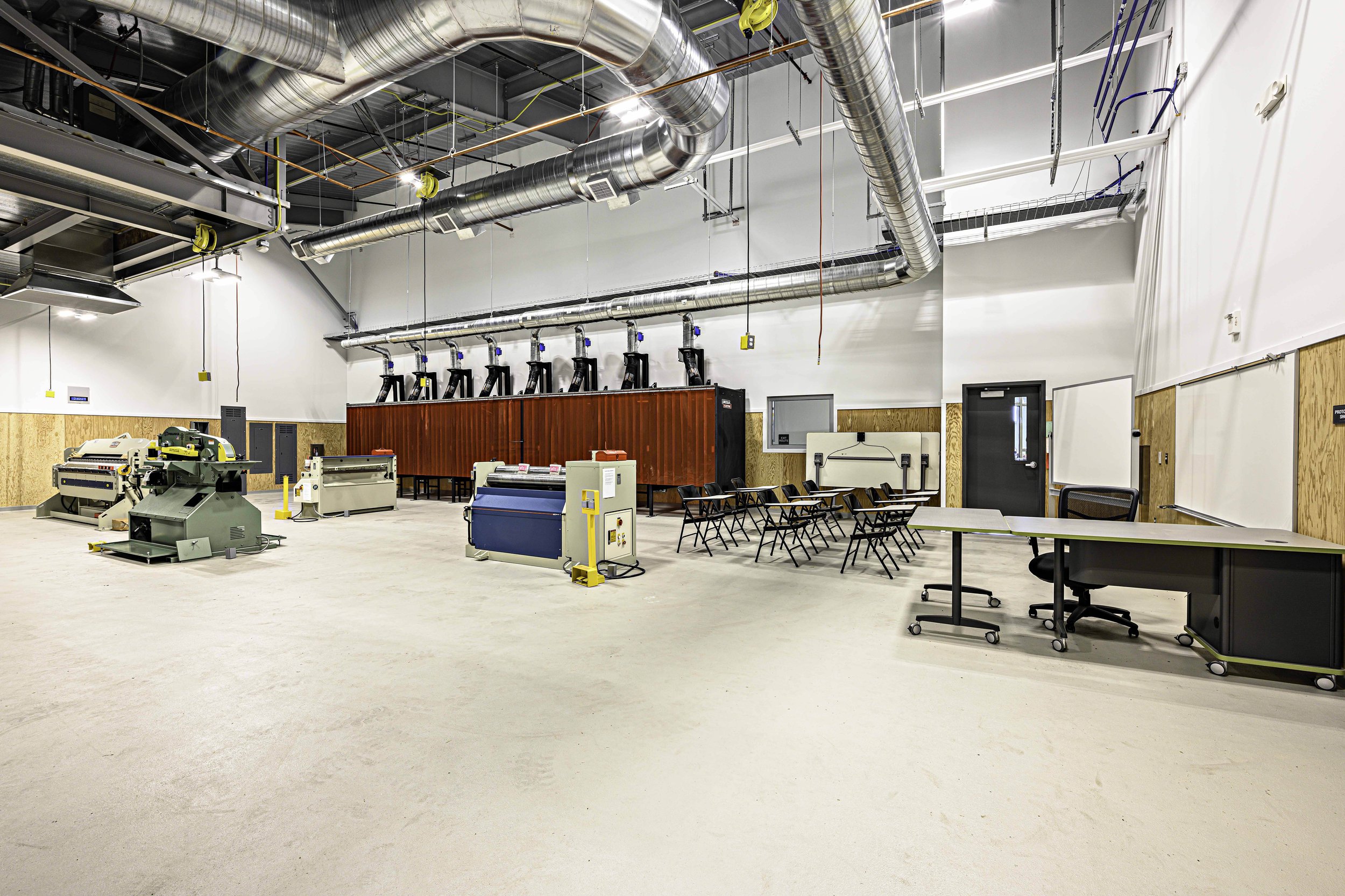 Empty industrial workspace with machinery, tables, and chairs.