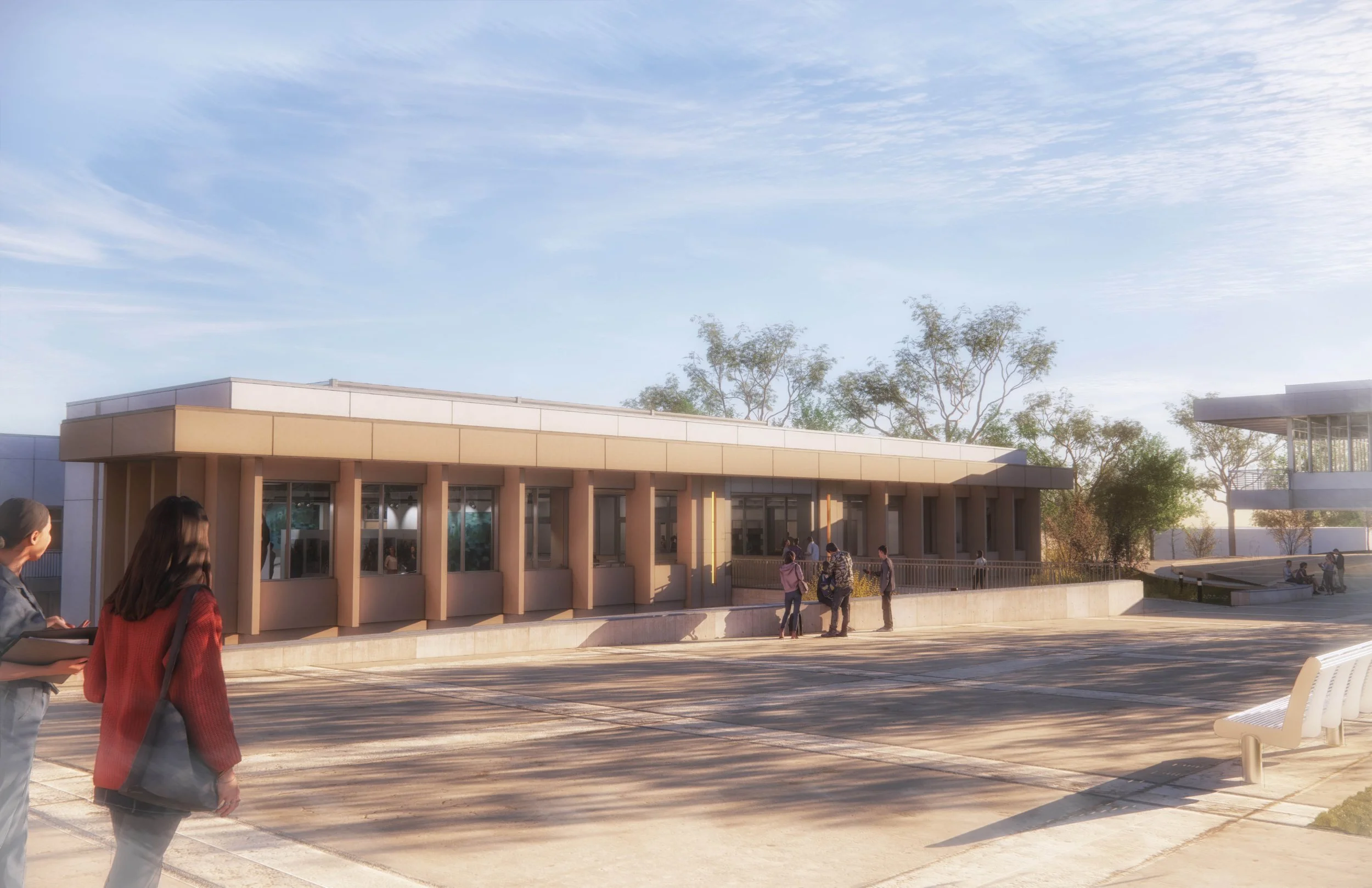 People walking near a modern building with large windows and a beige facade, trees in the background, under a partly cloudy sky.