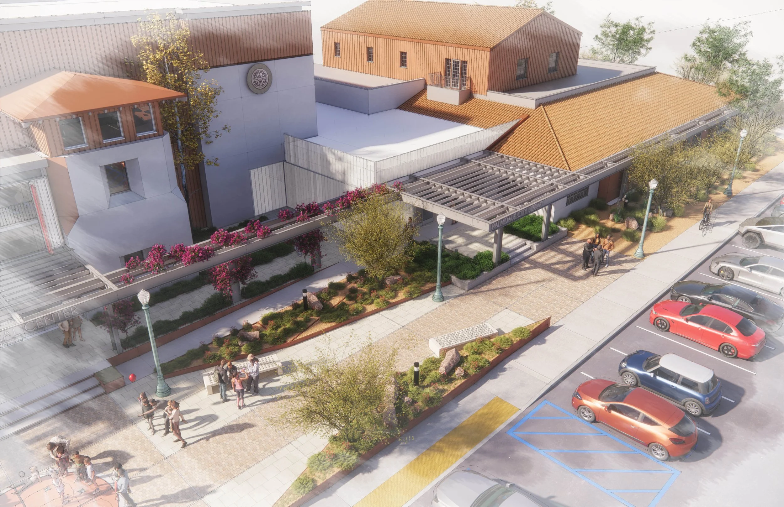 Aerial view of a modern building with a landscaped outdoor area, people walking and biking, parked cars, and street lamps.